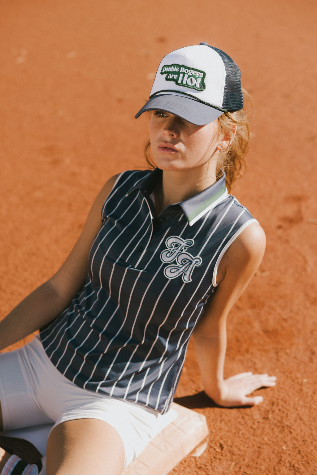 A woman wearing a sleeveless navy blue and white striped Moore Polo golf top.