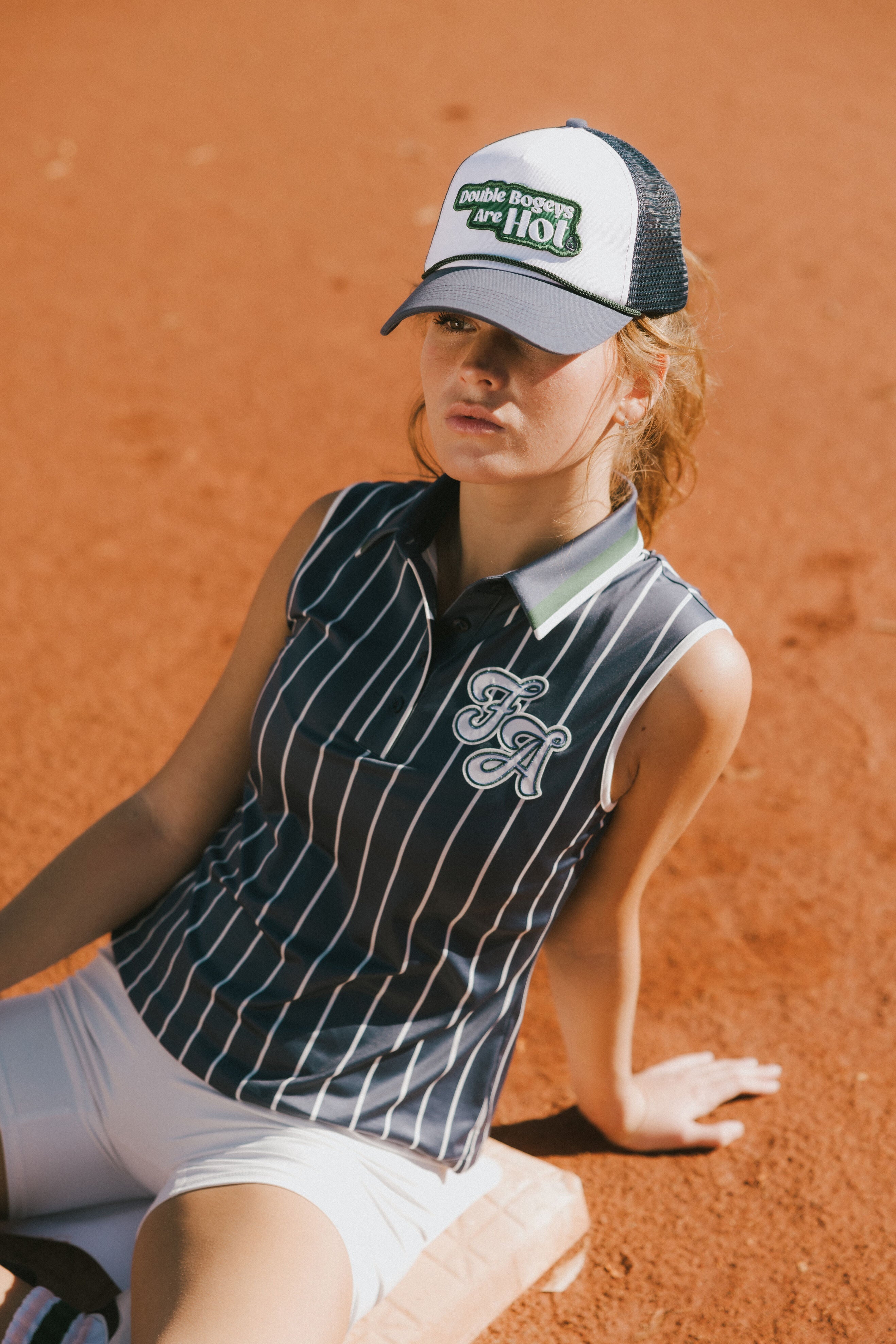A woman wearing a sleeveless navy blue and white striped Moore Polo golf top.