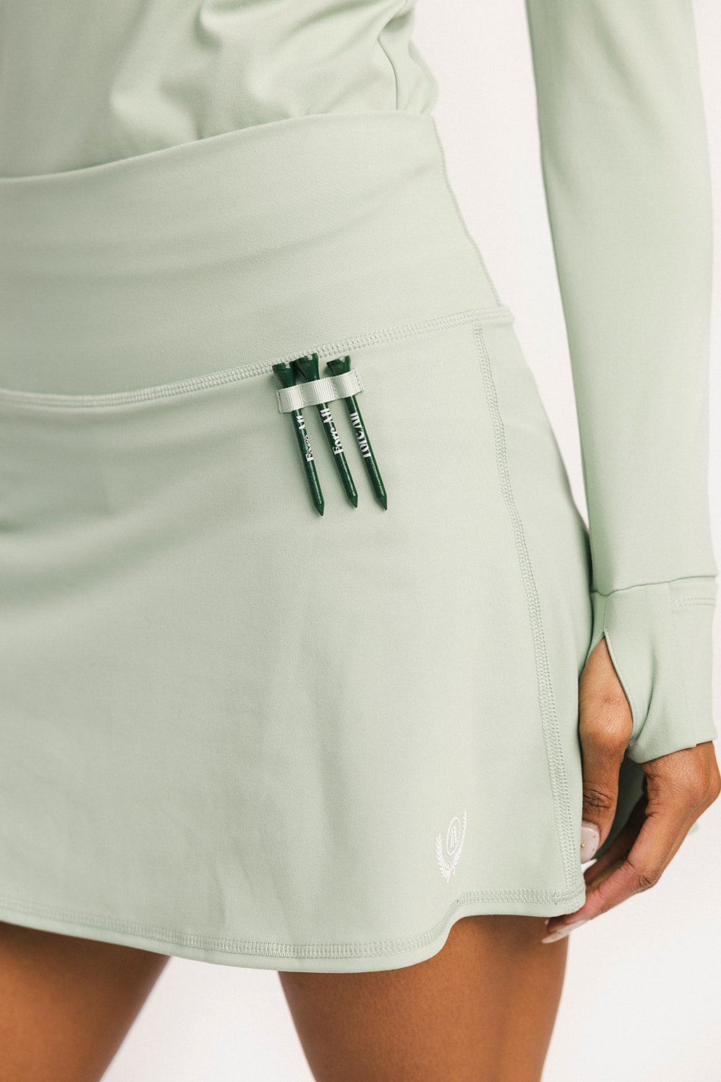 Light green skirt with a pocket containing three green items on a white background