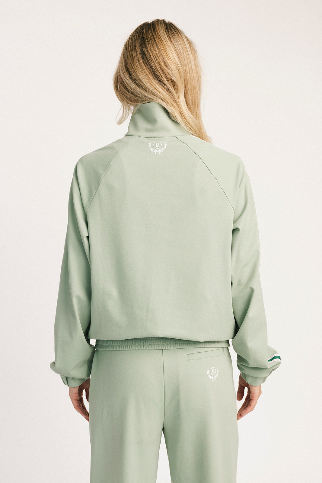 Person wearing a light green tracksuit with a brand logo on a white background