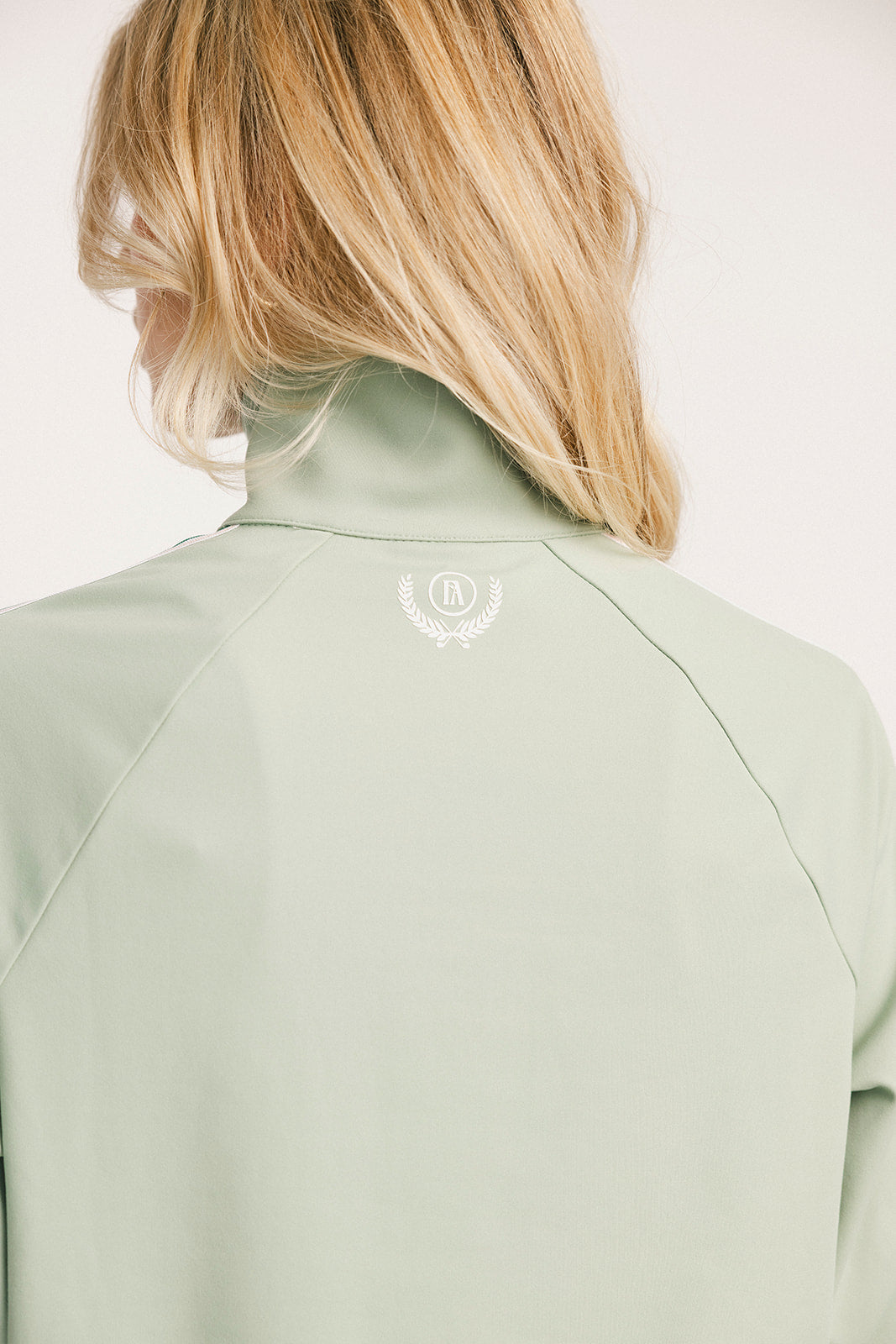Light green jacket with a brand logo on a plain background