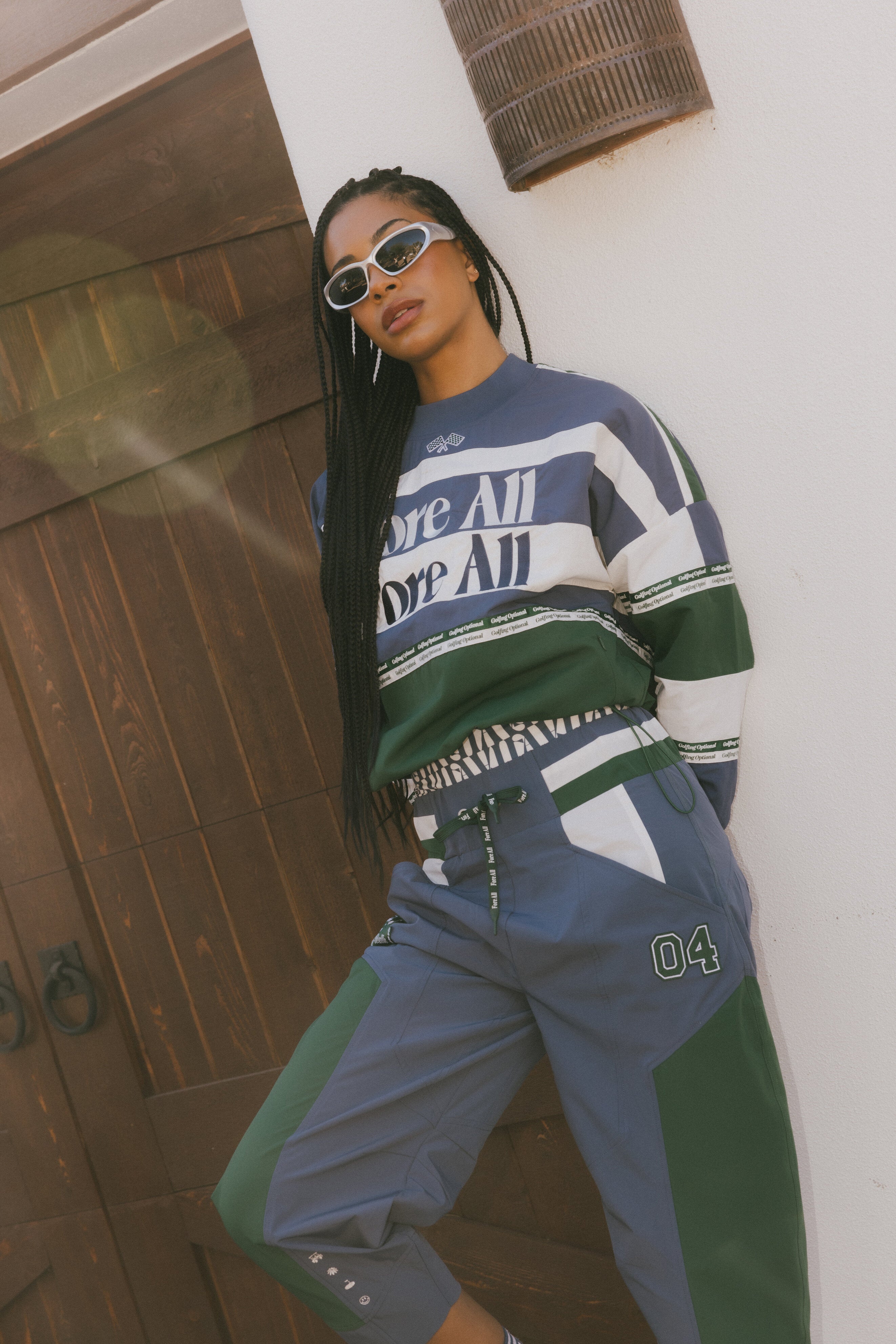 A woman wearing an indigo and green long-sleeved racing shirt with colorblocking and text embroidery.