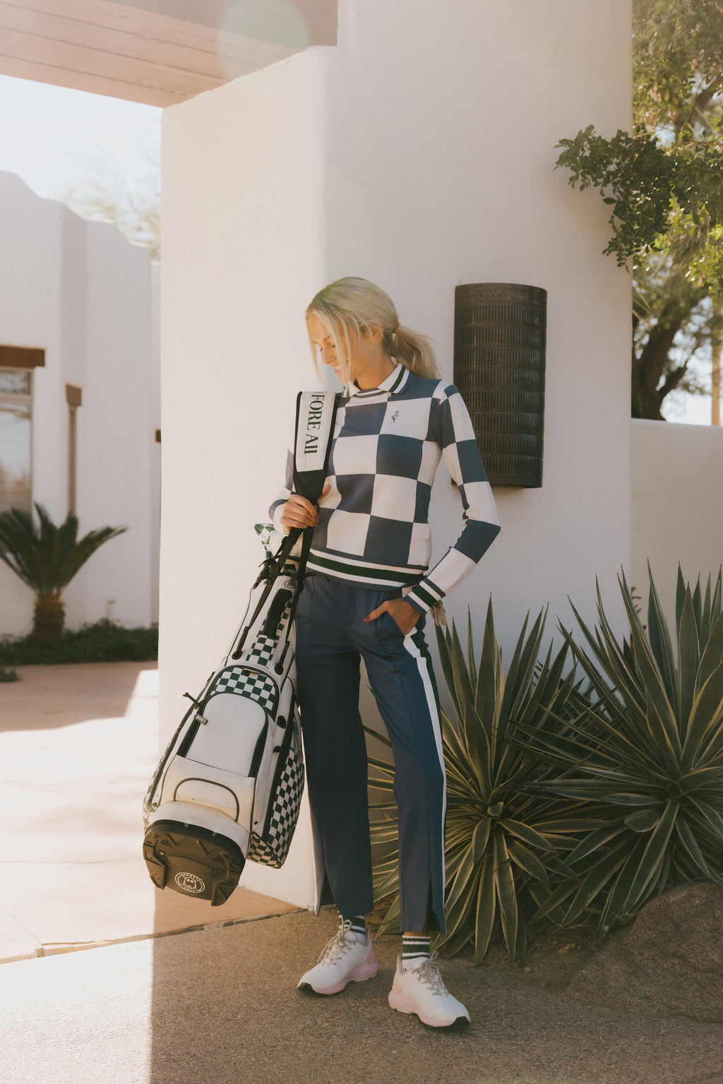 A woman wearing a sleeveless, checkered indigo and white sweater with a mock neck.