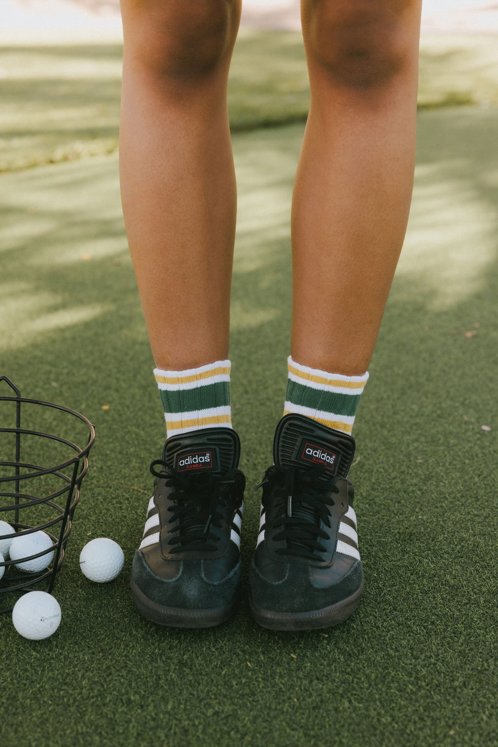 A person wearing retro ankle socks in mustard and green colors, paired with a black shoe.