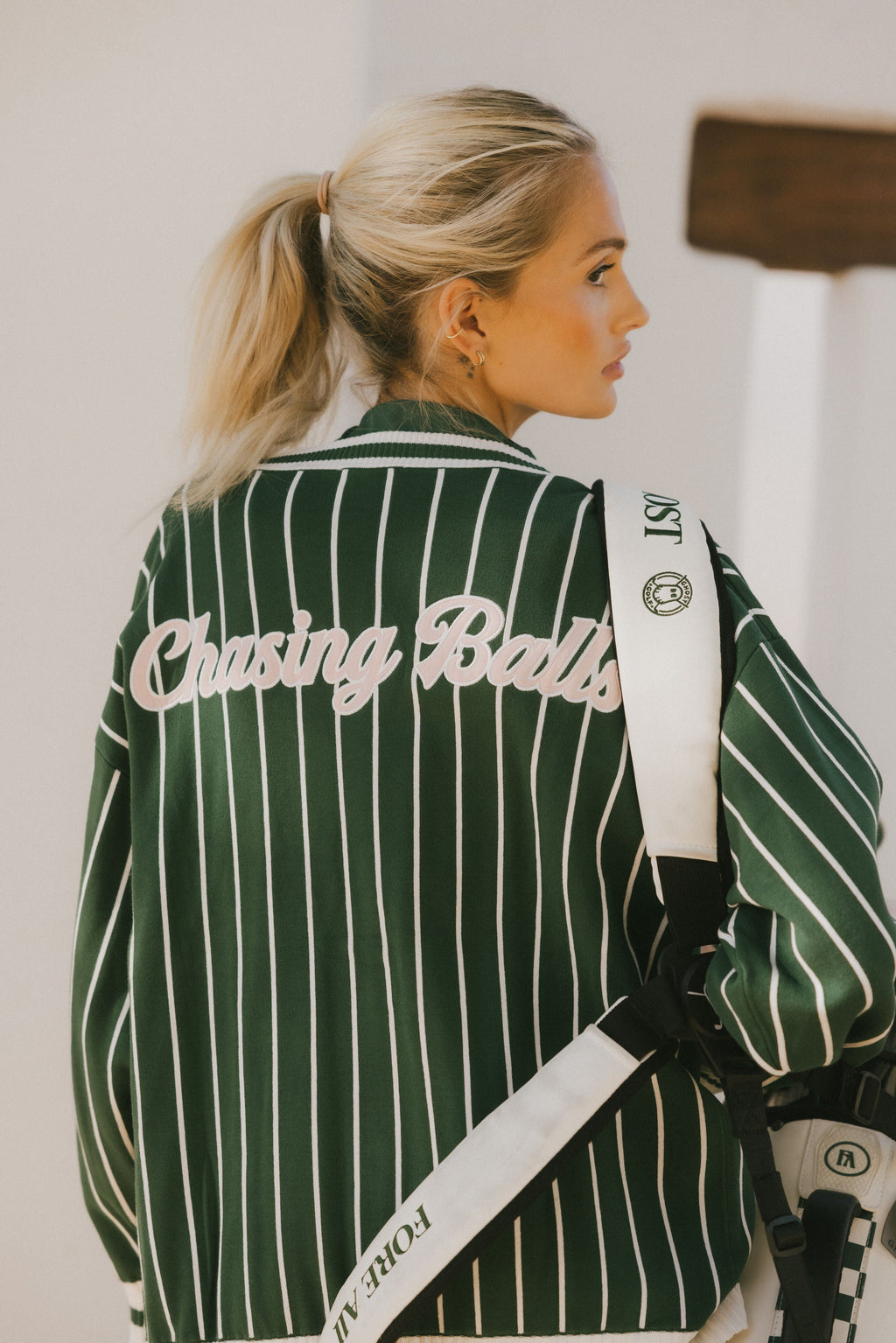 Person wearing a green and white striped cardigan with 'Chasing Balls' text.