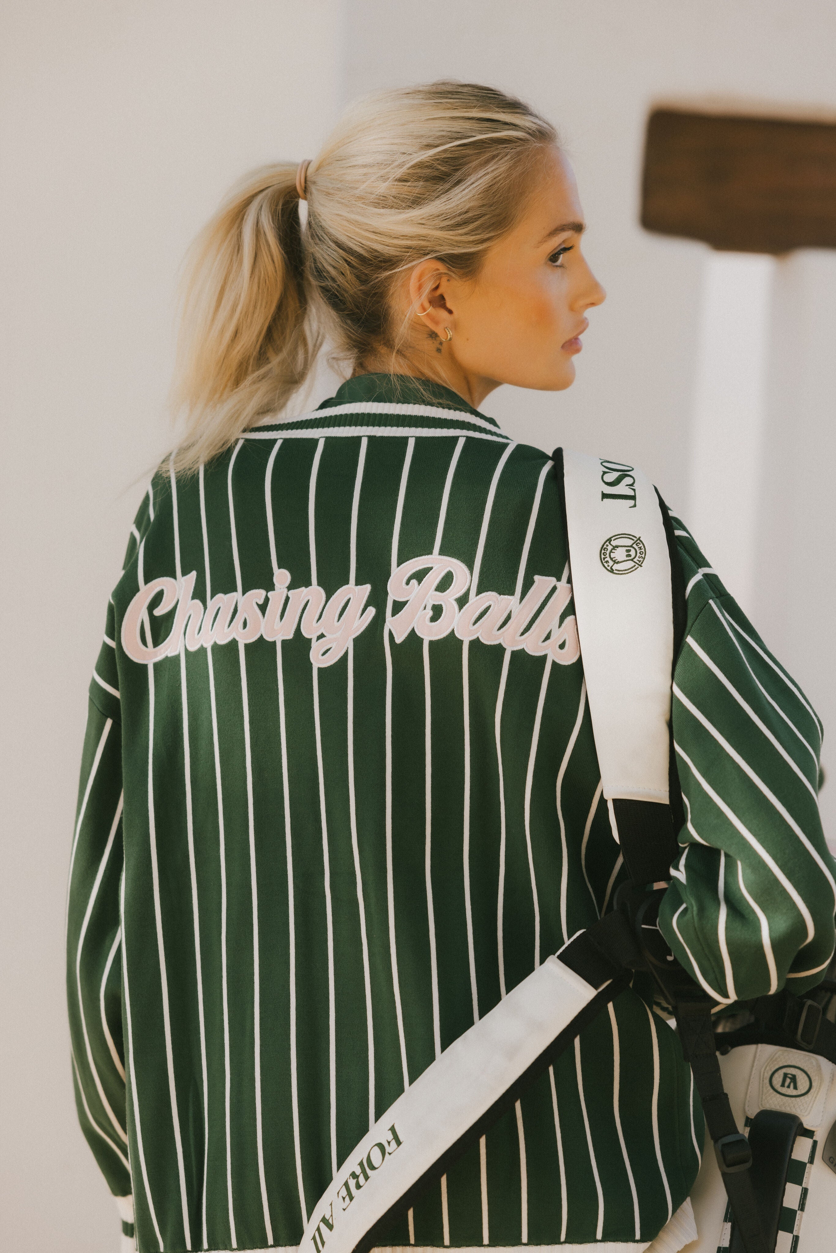 Person wearing a green and white striped cardigan with 'Chasing Balls' text.