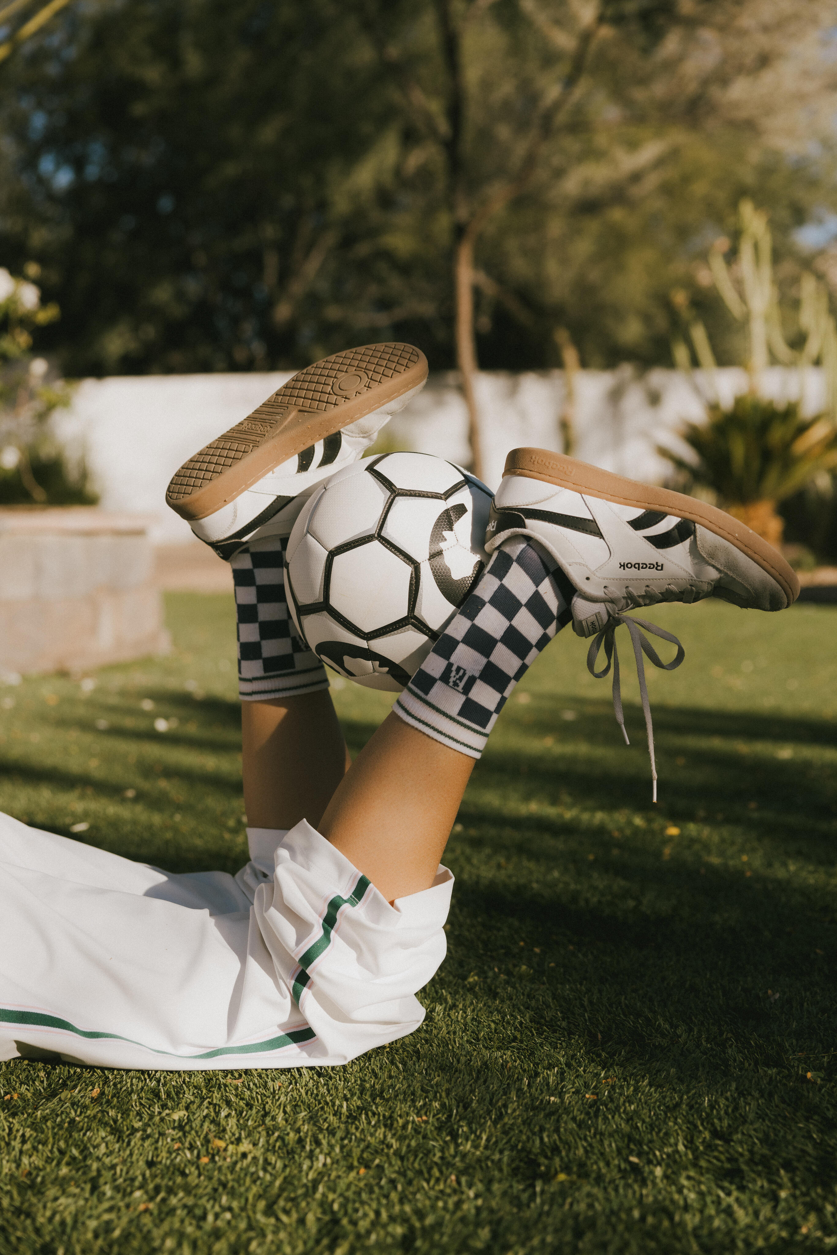 A model wearing the indigo charlie crew socks holding a soccer ball between her legs.