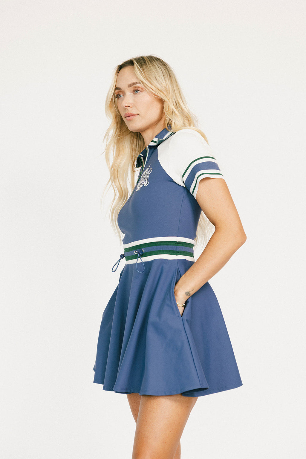 Woman wearing a blue dress with white and green accents on a white background.