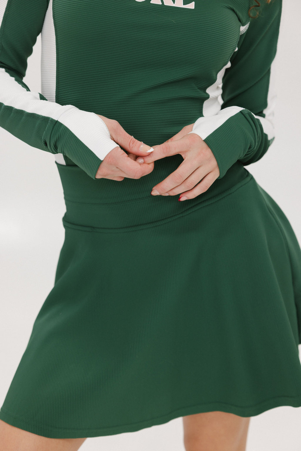A person wearing a high-waisted green skirt with a solid pattern and ribbed fabric.