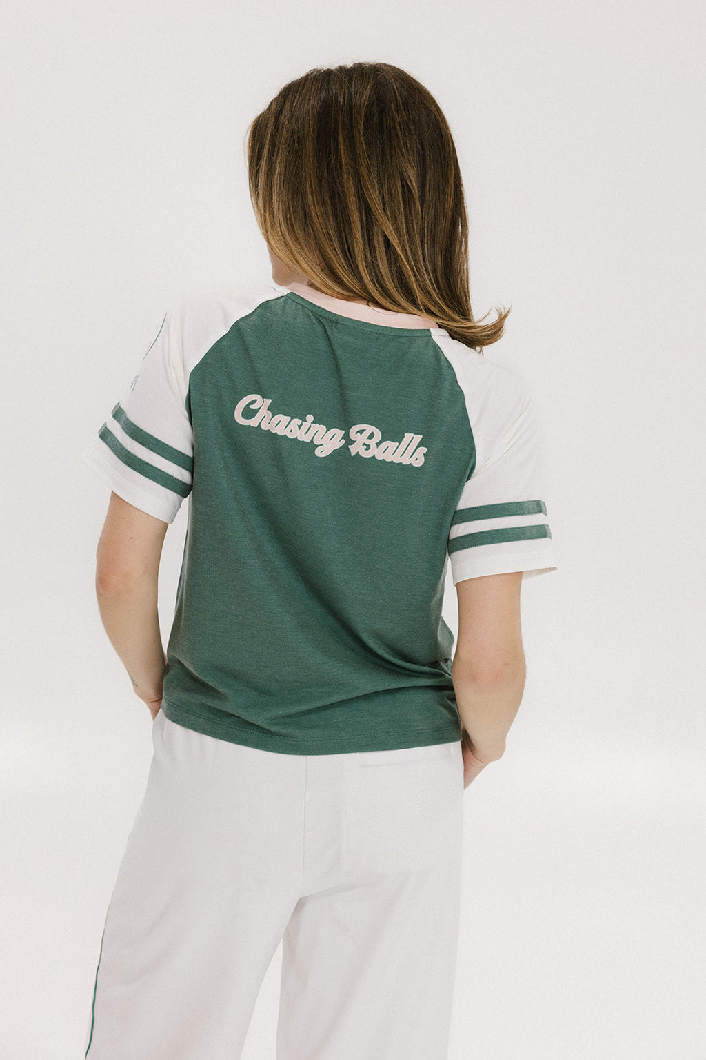A woman wearing a green and white boxy fit t-shirt with the number 04 on the front and bold lettering on the back, along with striped sleeves.