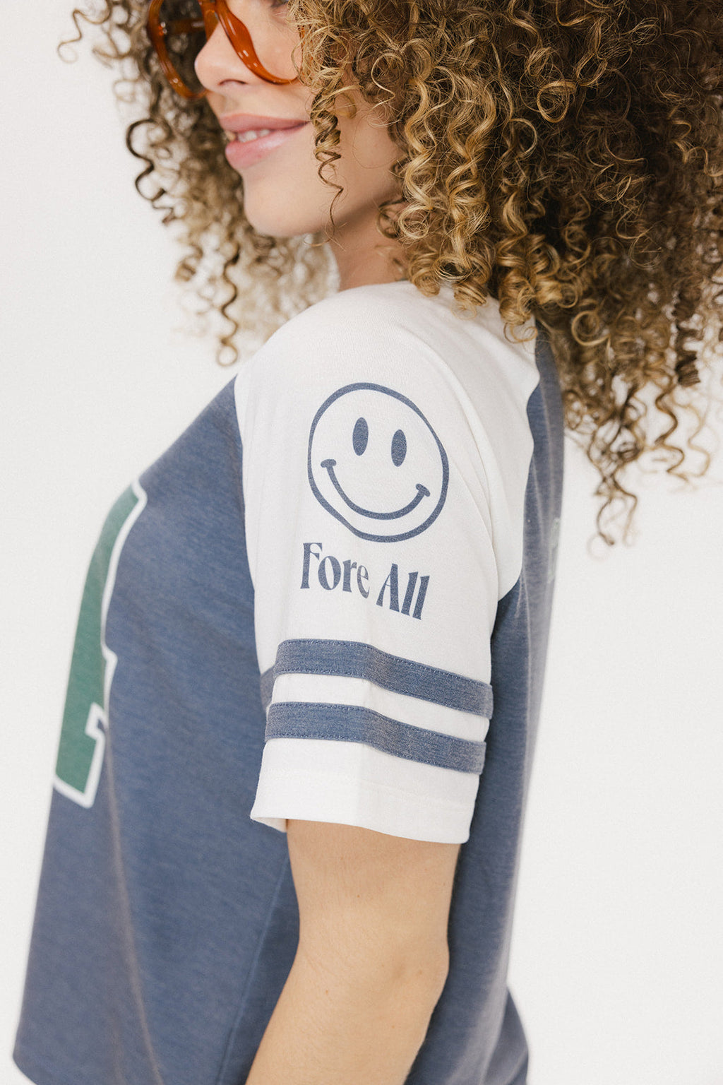 A woman wearing a blue and white striped t-shirt with the number '04' on it, paired with green pants.