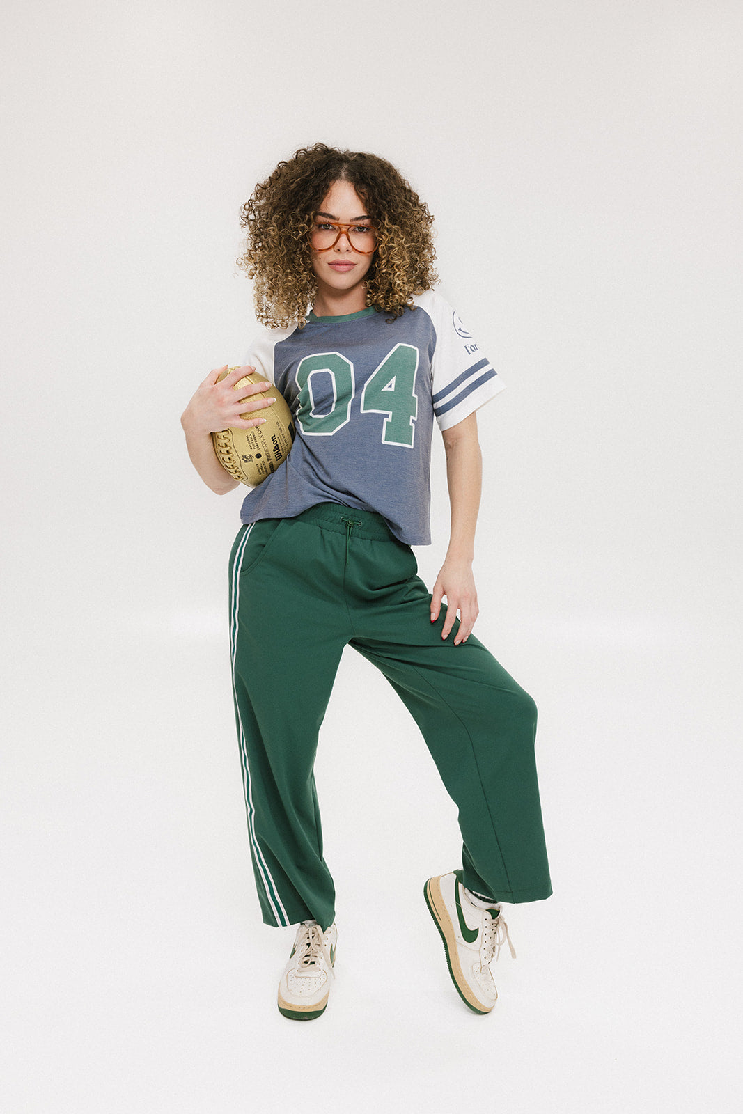 A woman wearing a blue and white striped t-shirt with the number '04' on it, paired with green pants.
