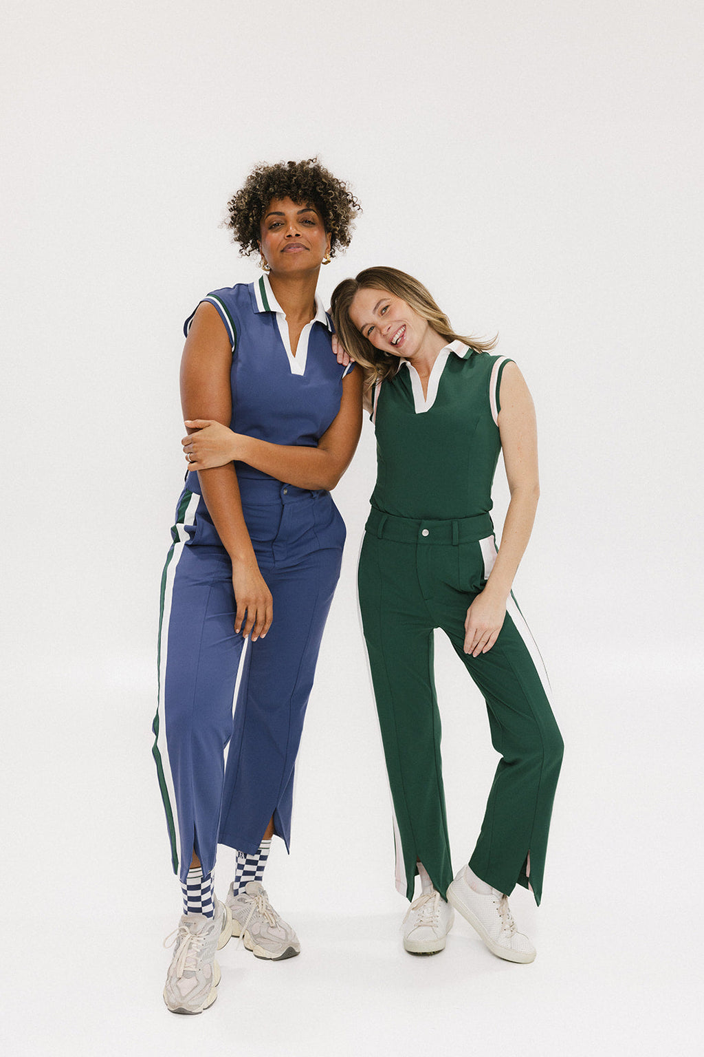 Two women wearing a sleeveless indigo and green polo with a striped collar and v-neck.