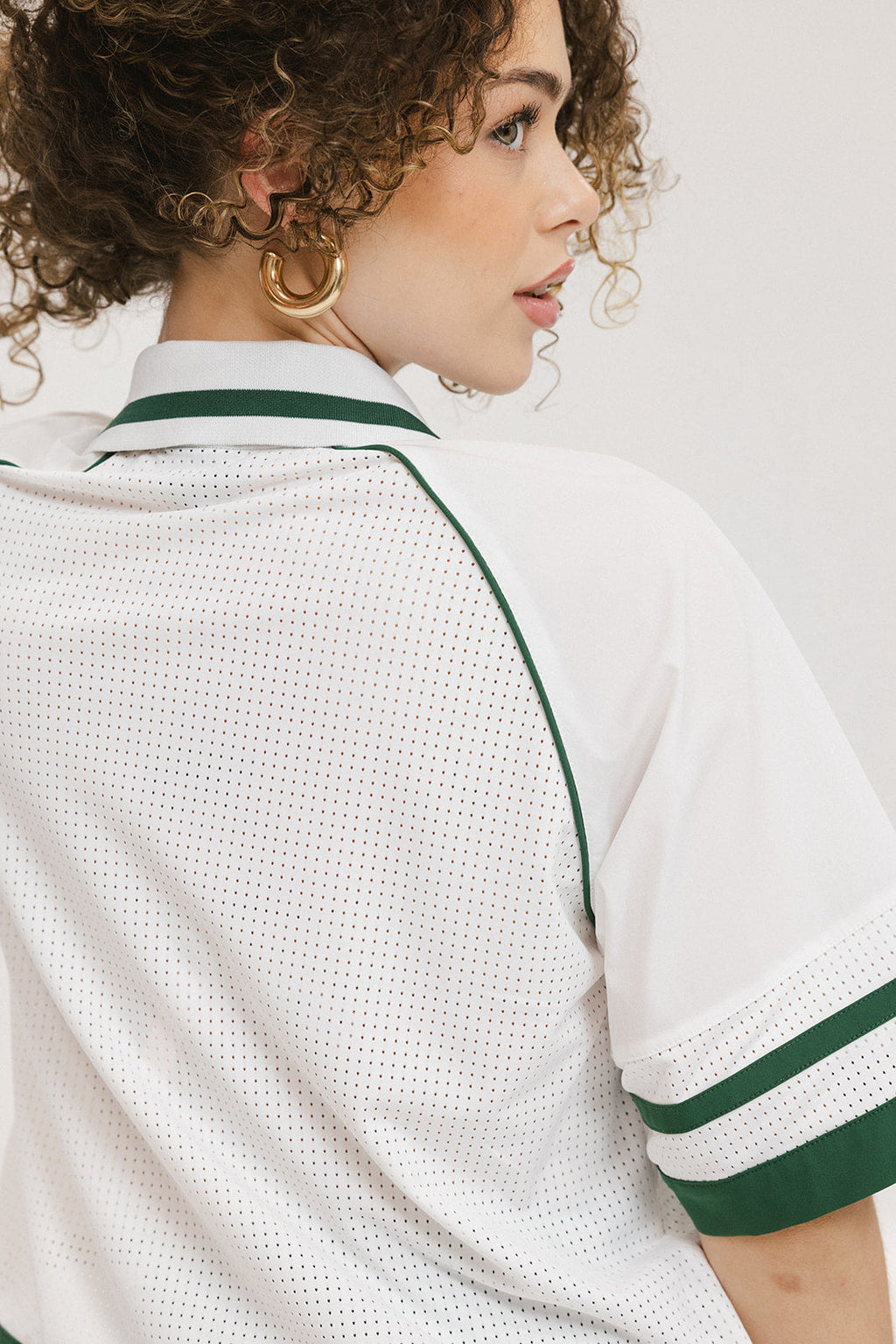 A person wearing a white polo shirt with green trim on the collar and sleeves.