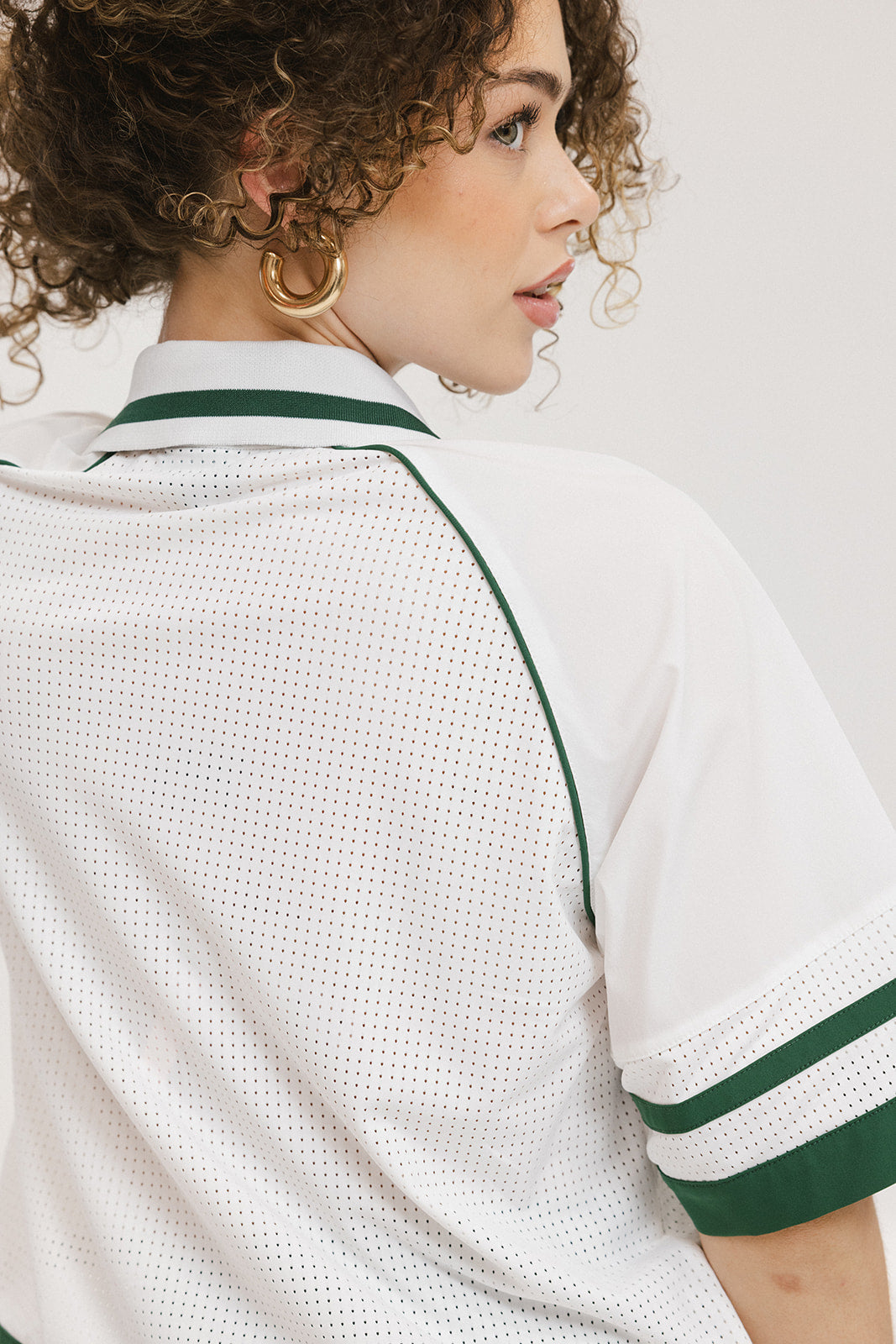 A person wearing a white polo shirt with green trim on the collar and sleeves.