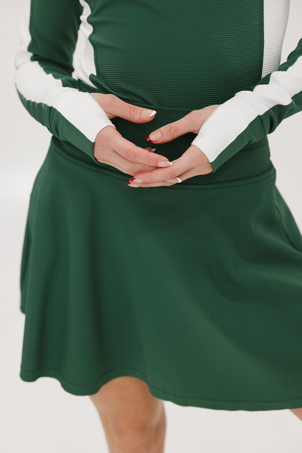 A female model wearing a long sleeve green and white ribbed baselayer top with raglan sleeves and colorblocking.