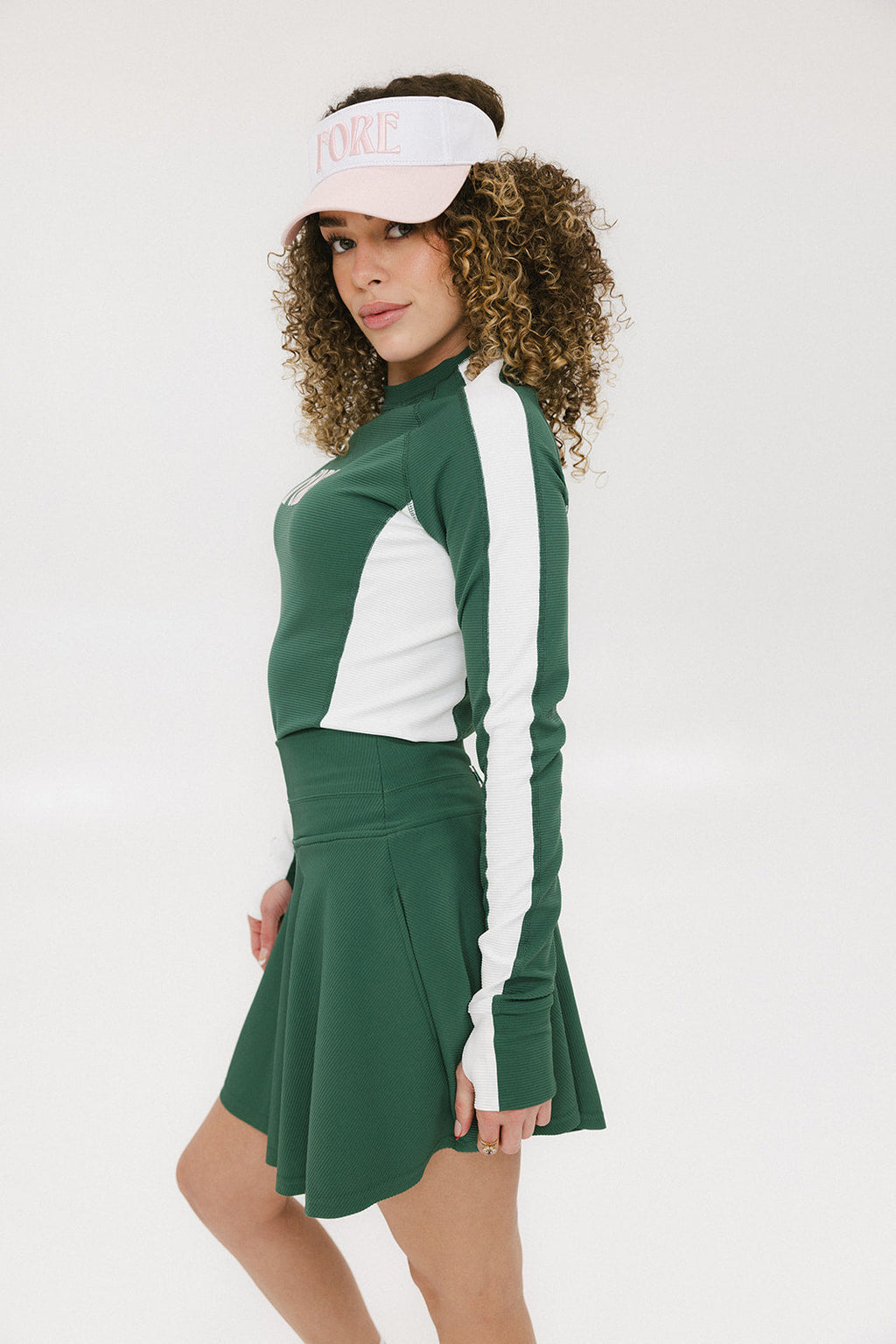 A female model wearing a long sleeve green and white ribbed baselayer top with raglan sleeves and colorblocking.