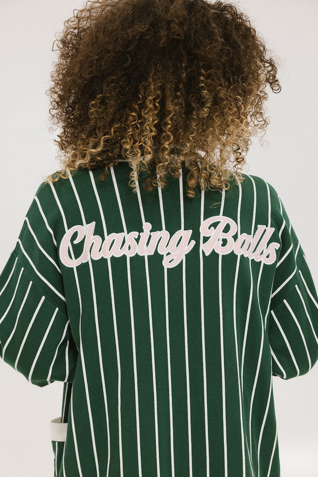 Person wearing a green and white striped cardigan with 'Chasing Balls' text.