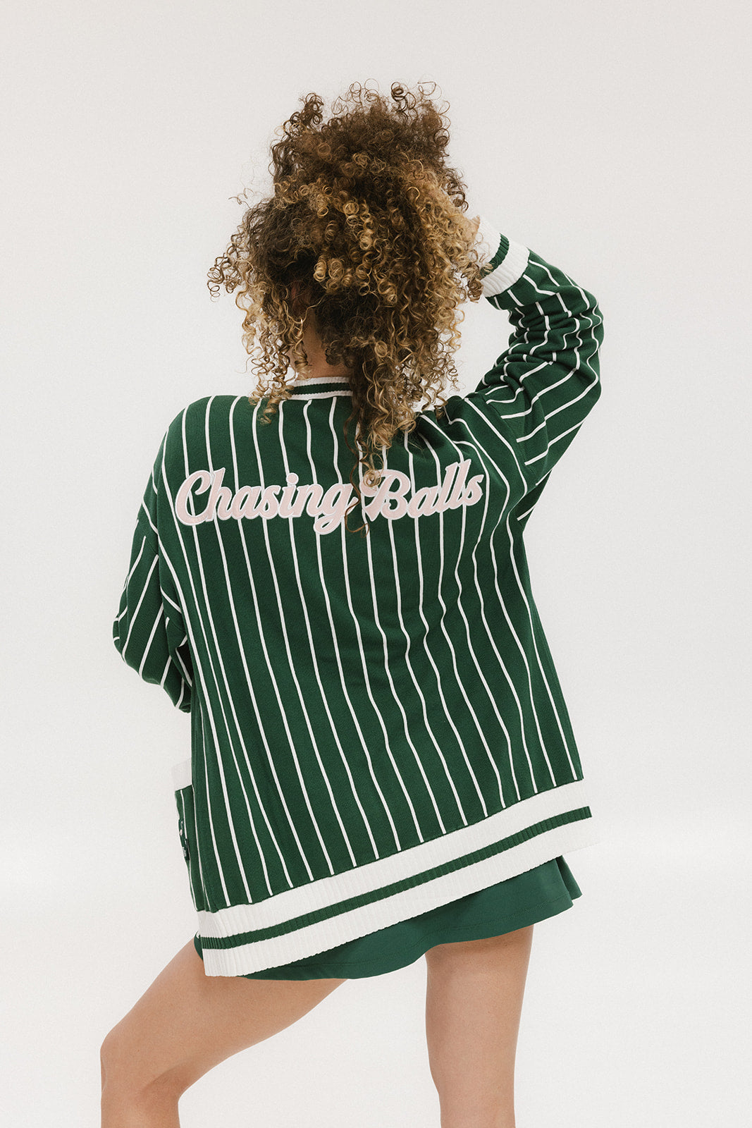 Person wearing a green and white striped cardigan with 'Chasing Balls' text.