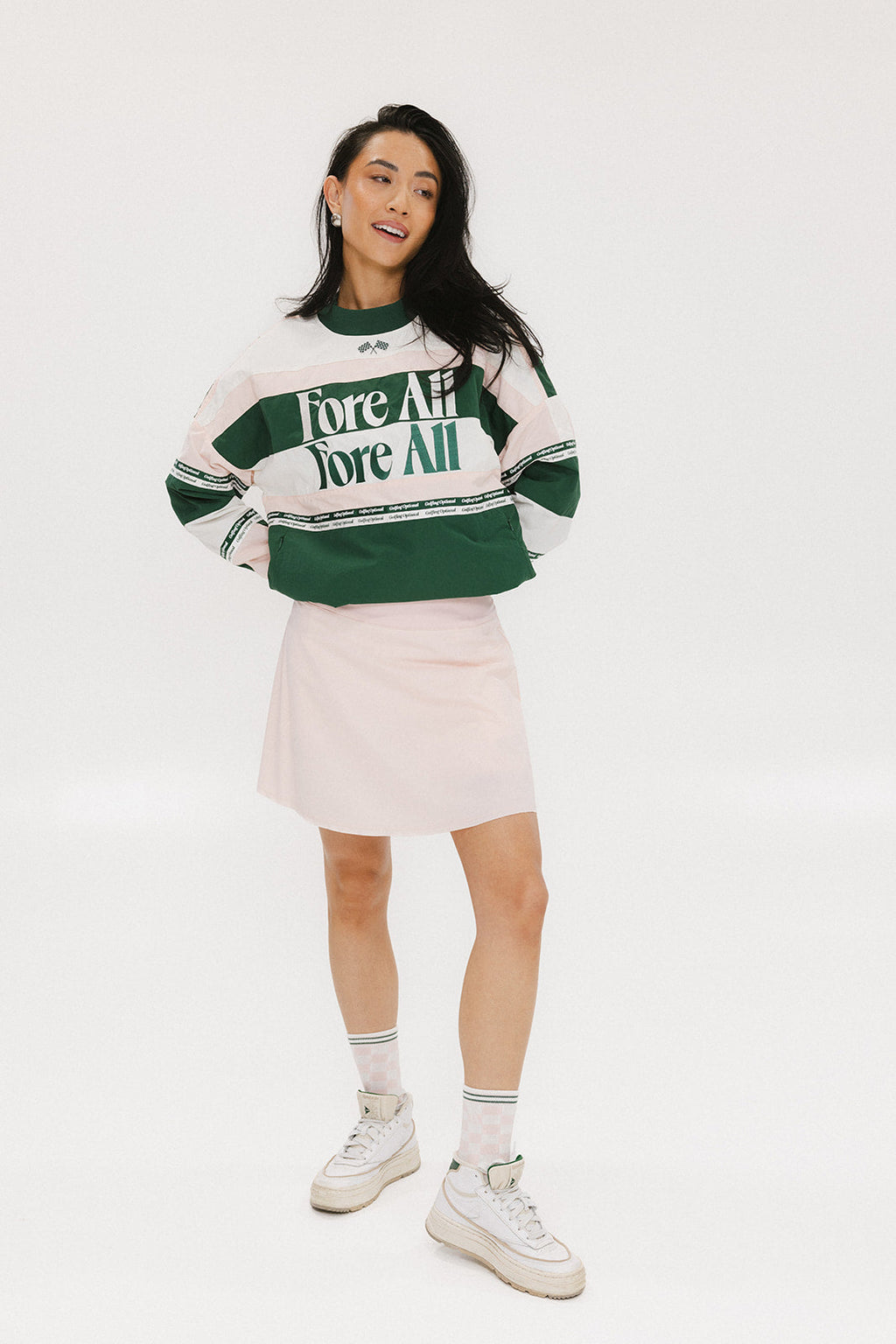 A woman wearing a green and pink racing shirt with colorblocking and text embroidery on it.