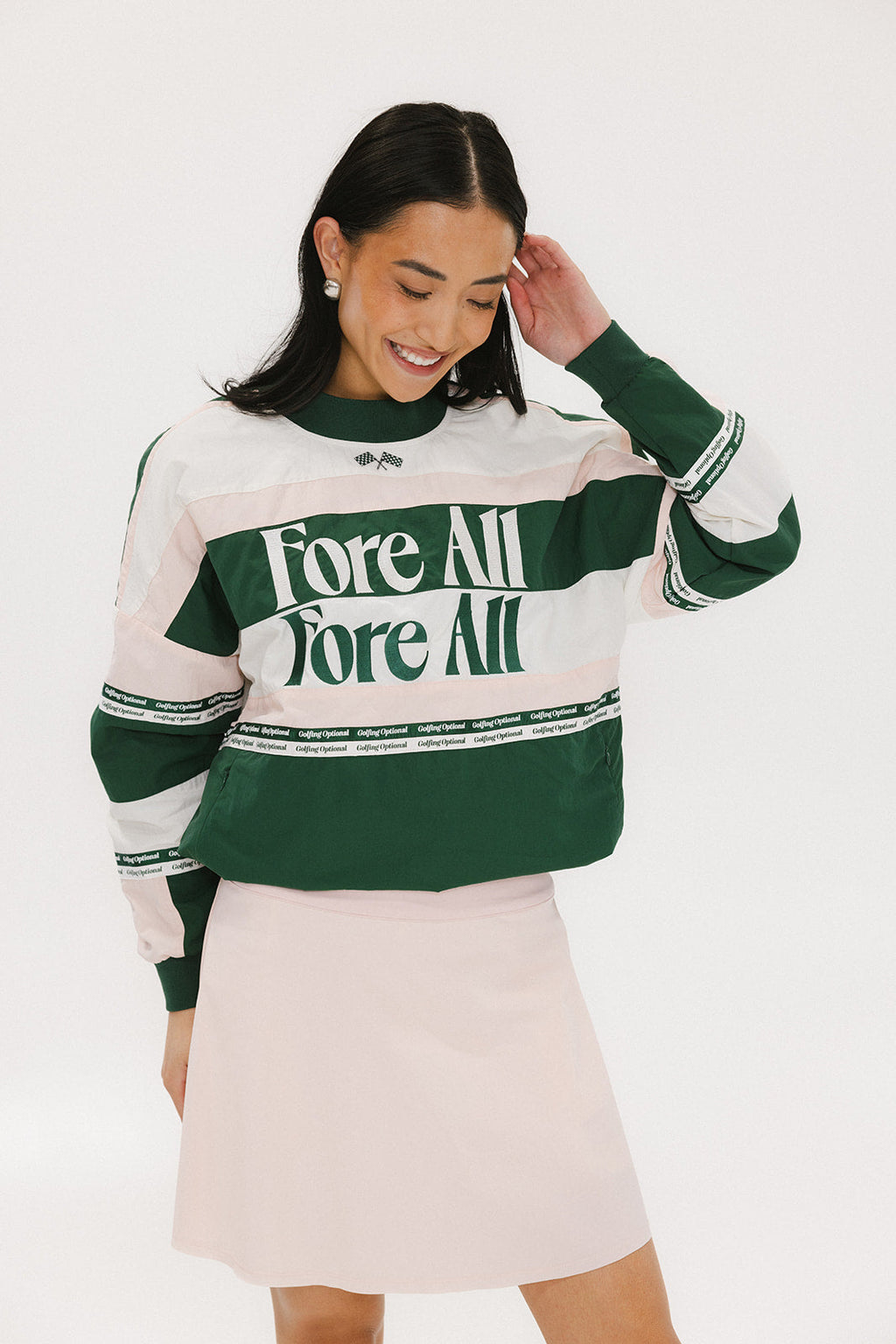A woman wearing a green and pink racing shirt with colorblocking and text embroidery on it.