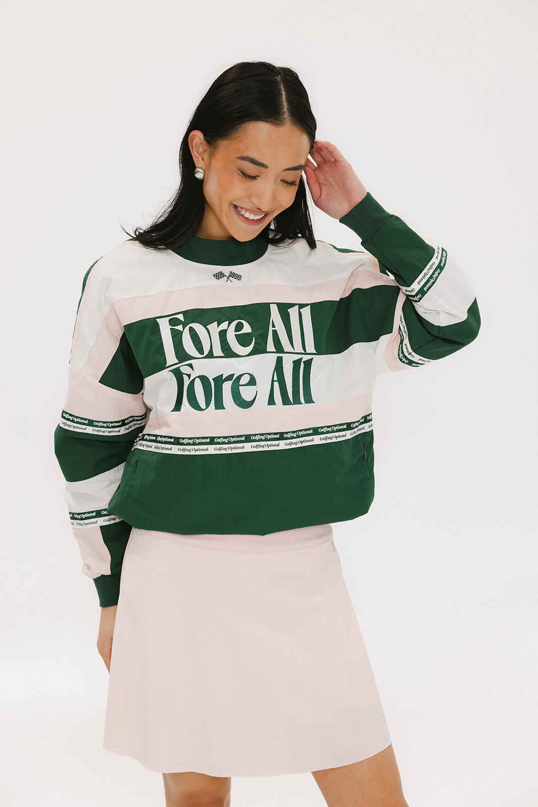 A woman wearing a green and pink racing shirt with colorblocking and text embroidery on it.