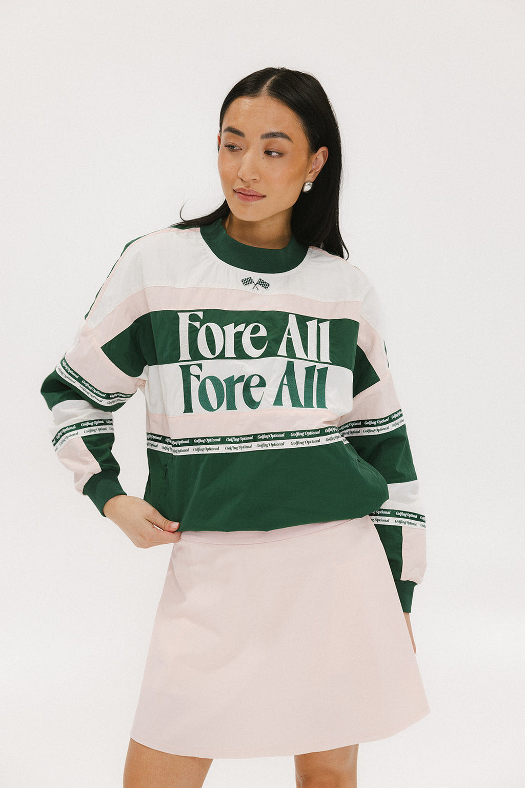 A woman wearing a green and pink racing shirt with colorblocking and text embroidery on it.