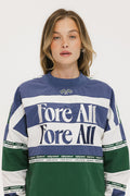 A woman wearing an indigo and green long-sleeved racing shirt with colorblocking and text embroidery.