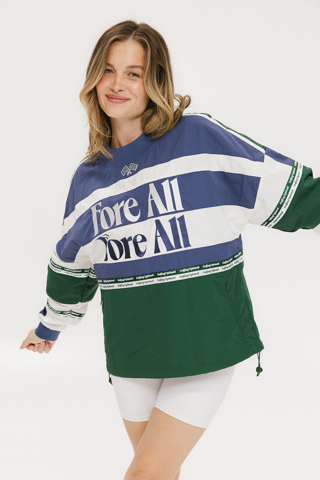 A woman wearing an indigo and green long-sleeved racing shirt with colorblocking and text embroidery.