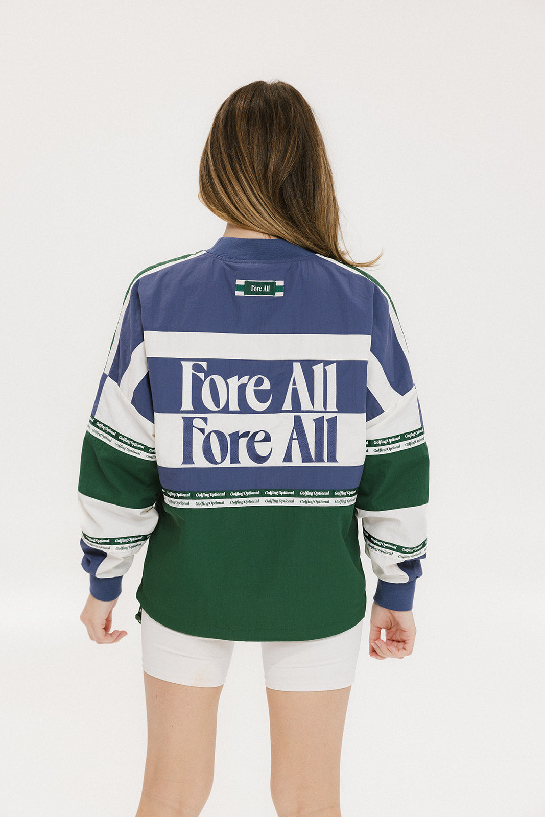 A woman wearing an indigo and green long-sleeved racing shirt with colorblocking and text embroidery.