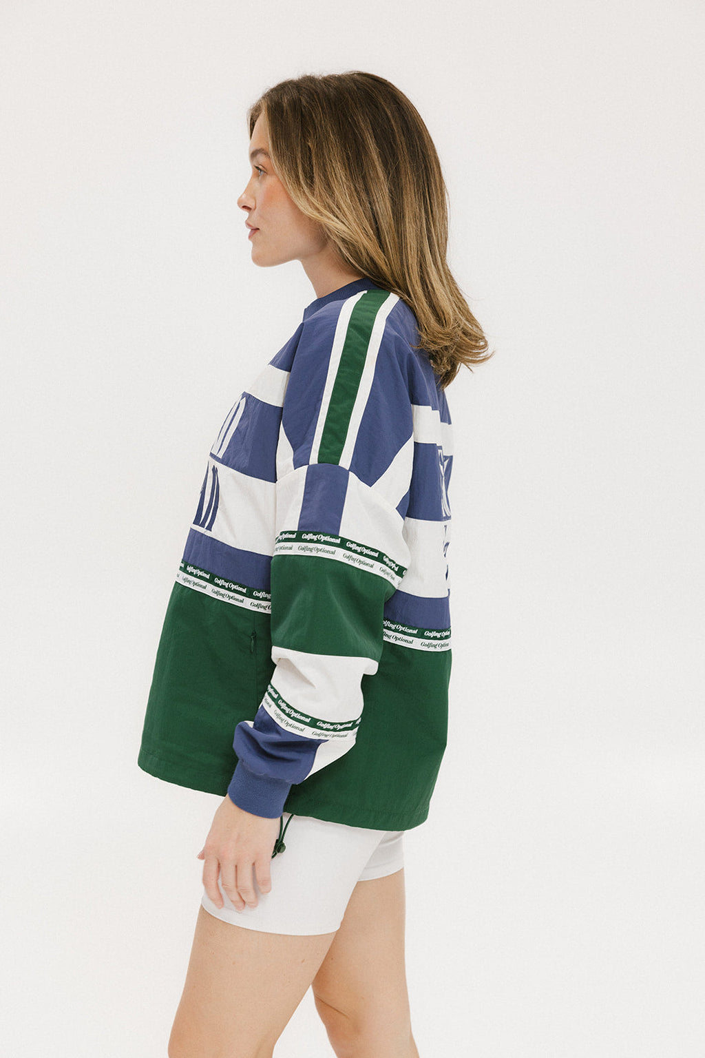 A woman wearing an indigo and green long-sleeved racing shirt with colorblocking and text embroidery.