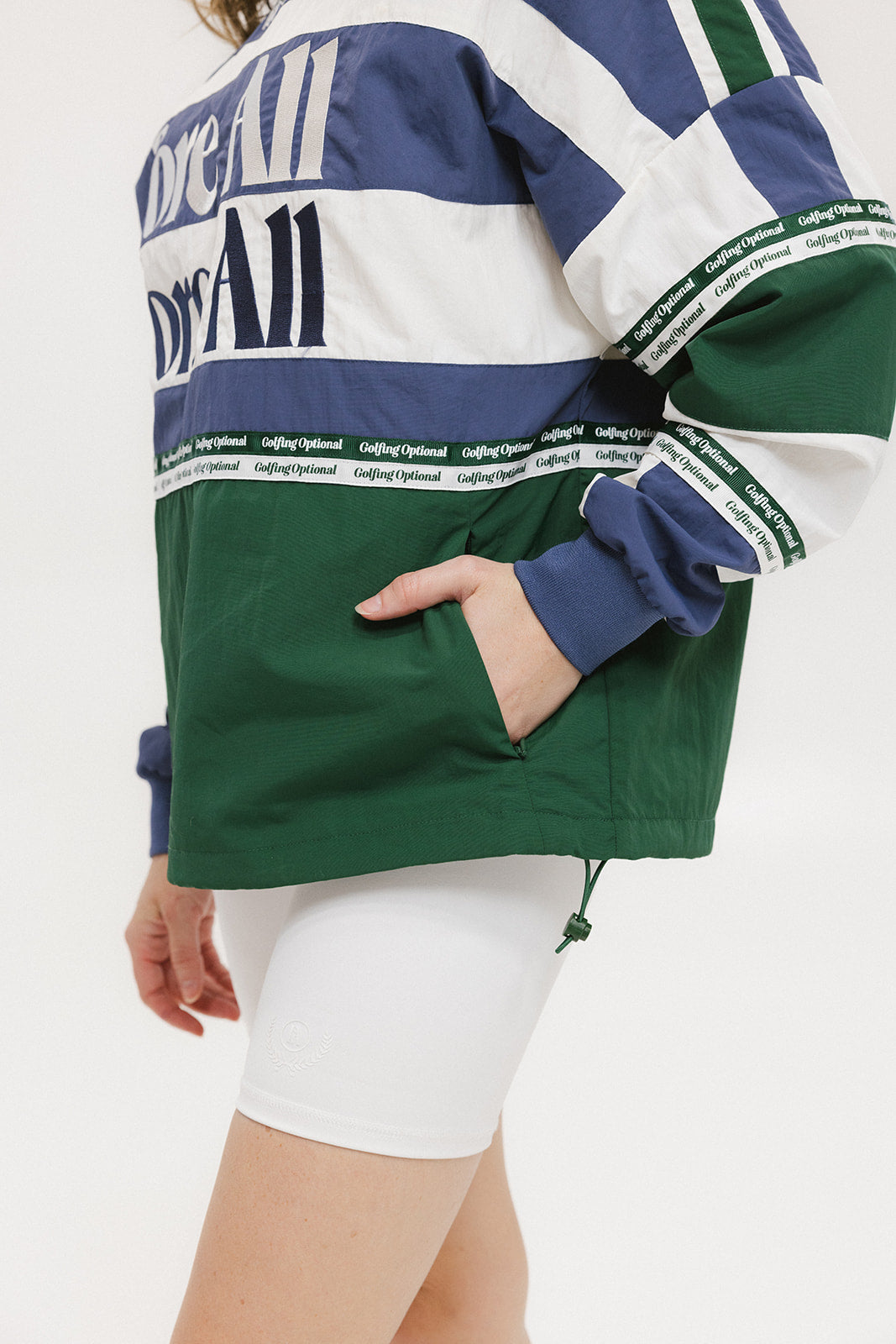A woman wearing an indigo and green long-sleeved racing shirt with colorblocking and text embroidery.