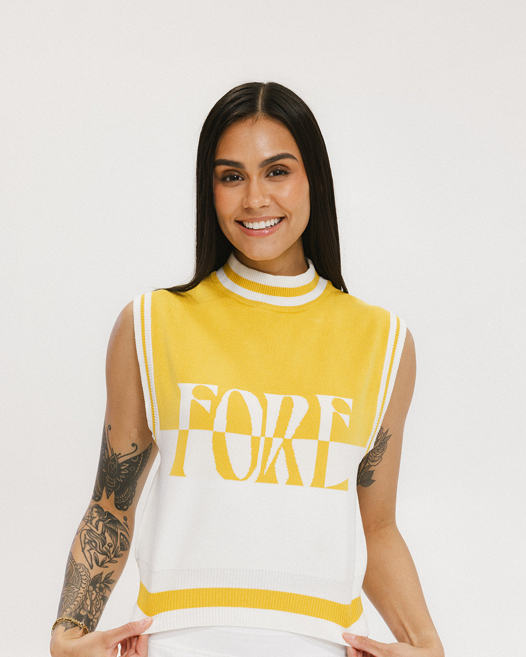 A sleeveless mock-neck sweater with intarsia knit design, featuring horizontal yellow and white stripes and the word 'FORE' printed across the chest.