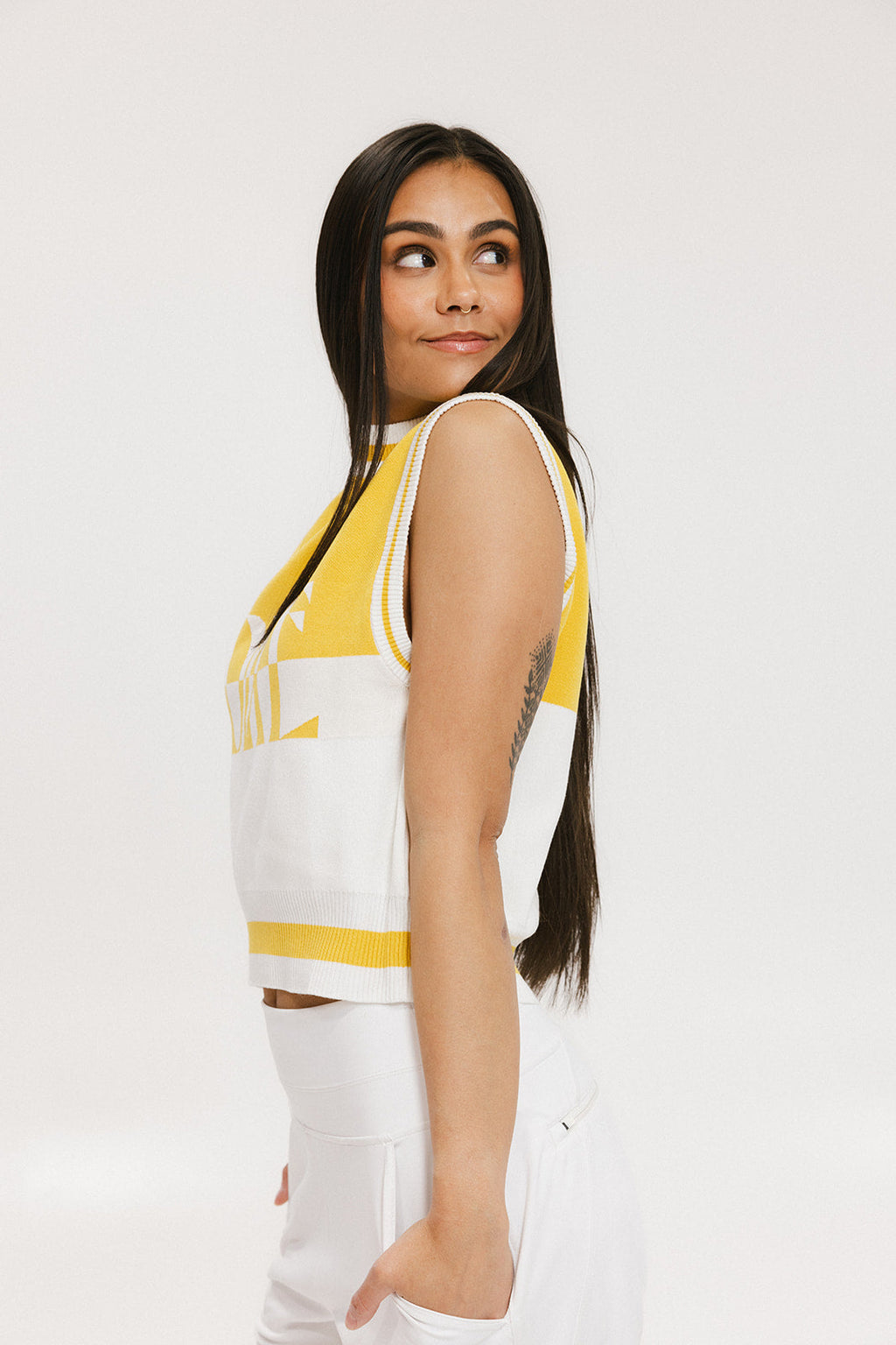 A sleeveless mock-neck sweater with intarsia knit design, featuring horizontal yellow and white stripes and the word 'FORE' printed across the chest.