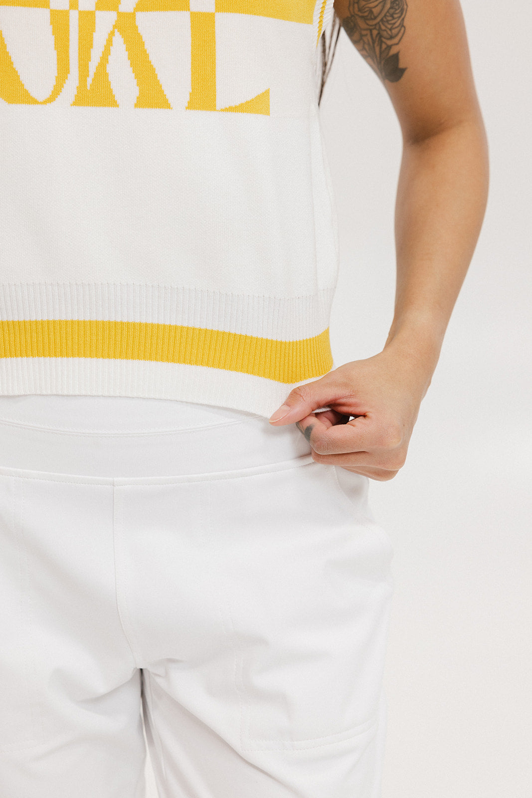 A sleeveless mock-neck sweater with intarsia knit design, featuring horizontal yellow and white stripes and the word 'FORE' printed across the chest.