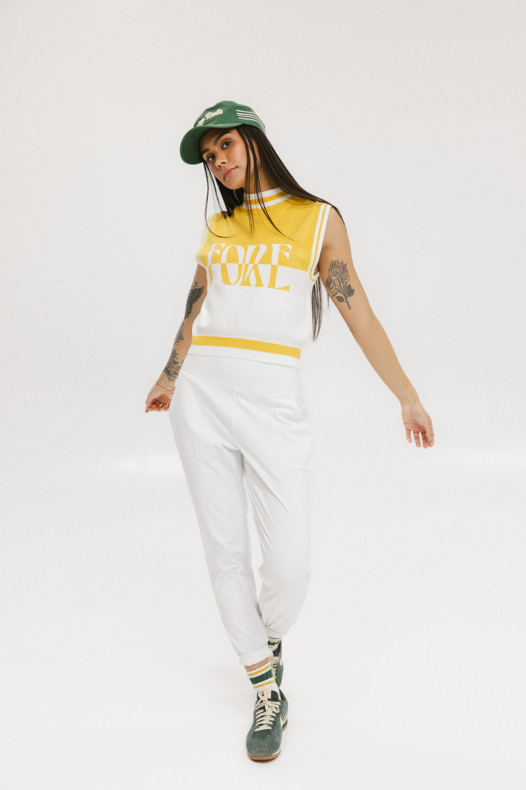 A sleeveless mock-neck sweater with intarsia knit design, featuring horizontal yellow and white stripes and the word 'FORE' printed across the chest.