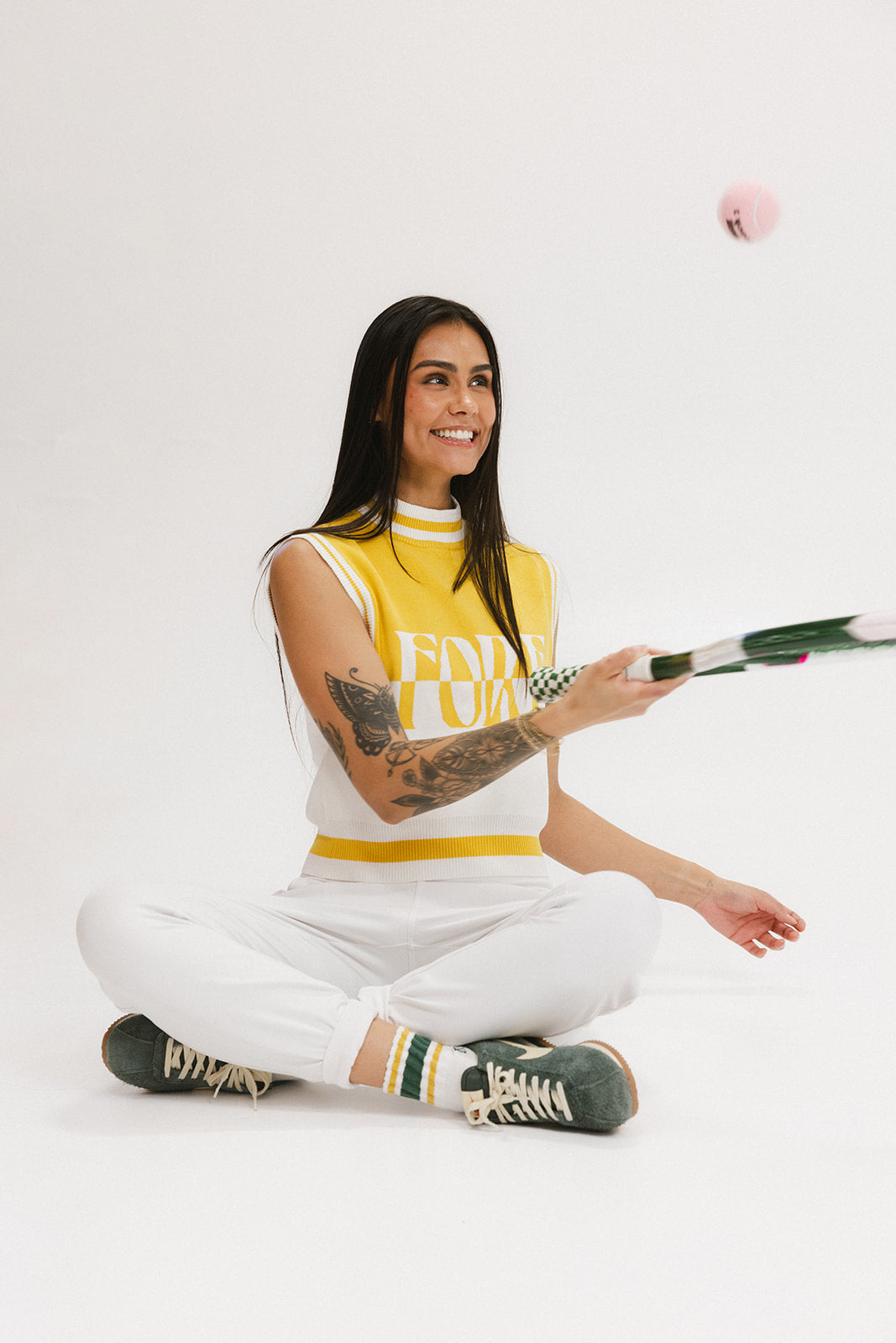 A sleeveless mock-neck sweater with intarsia knit design, featuring horizontal yellow and white stripes and the word 'FORE' printed across the chest.