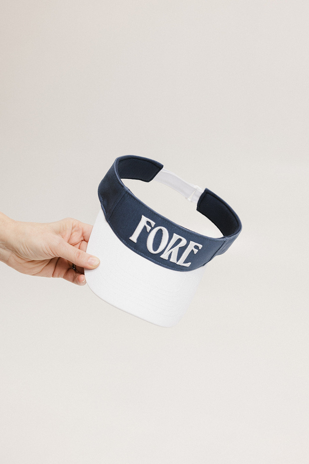 A hand holding a visor with 'FORE' written in bold letters on the front and '04' on the back, against a white background.