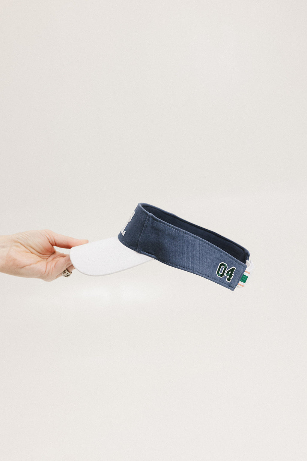 A hand holding a visor with 'FORE' written in bold letters on the front and '04' on the back, against a white background.