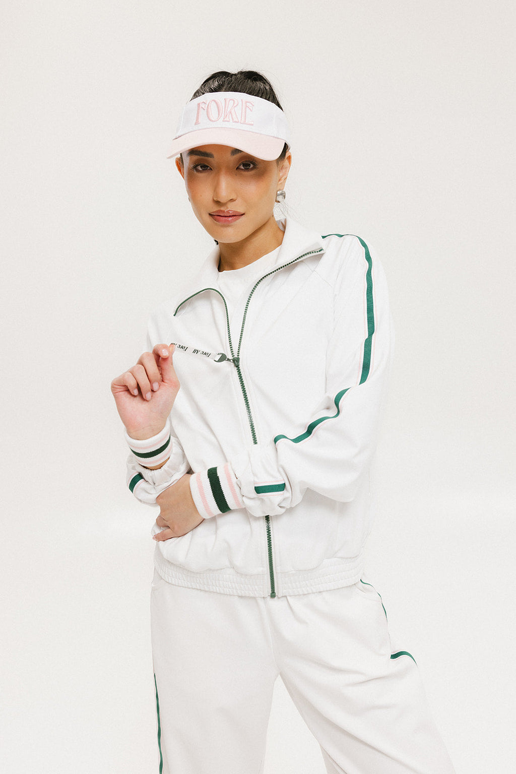 A hand holding a two-toned visor with 'FORE' logo in pink and white colors.