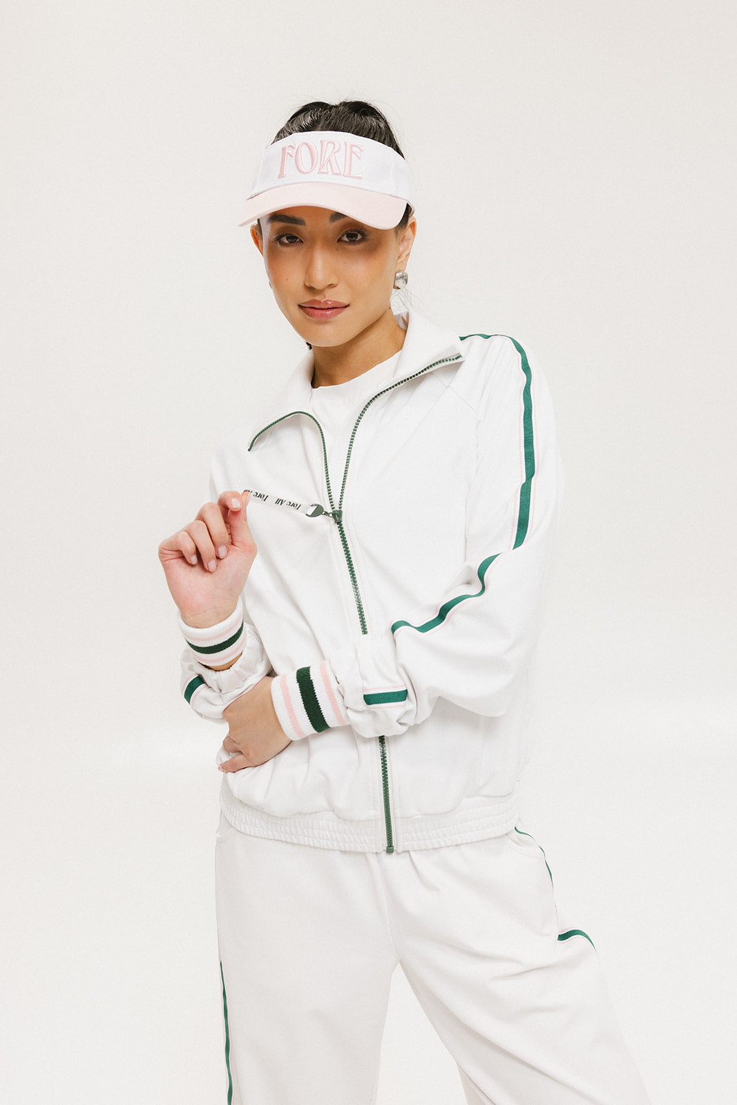 A hand holding a two-toned visor with 'FORE' logo in pink and white colors.