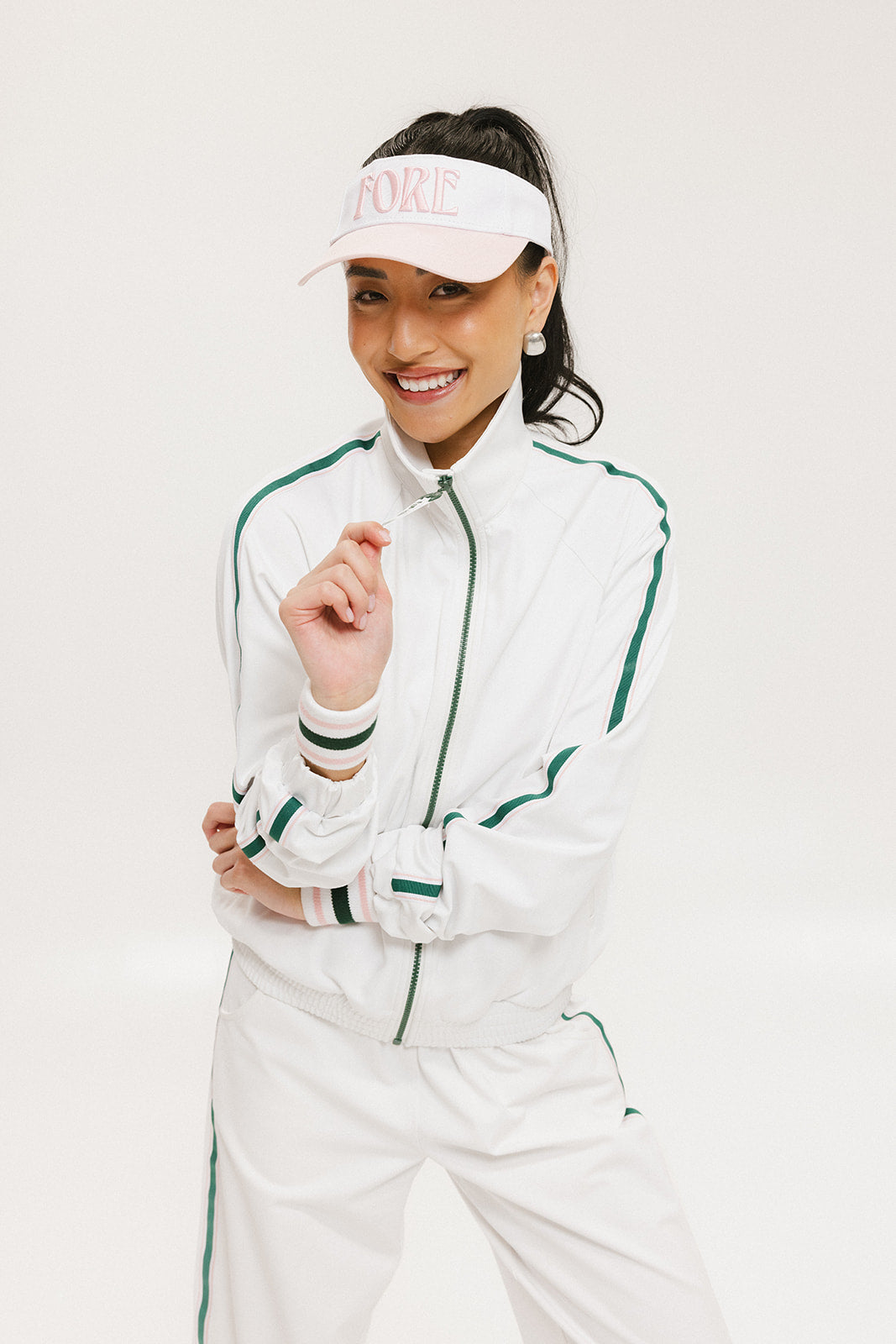 A hand holding a two-toned visor with 'FORE' logo in pink and white colors.
