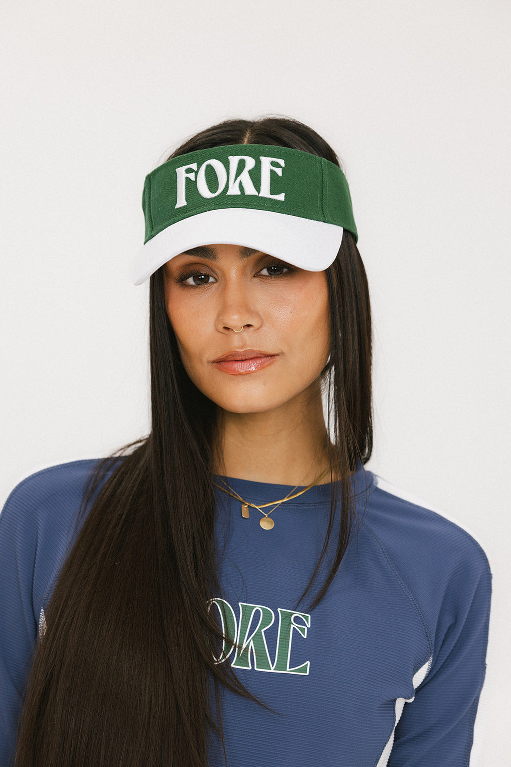 A model wearing a green and white visor with the text 'FORE' across the front.