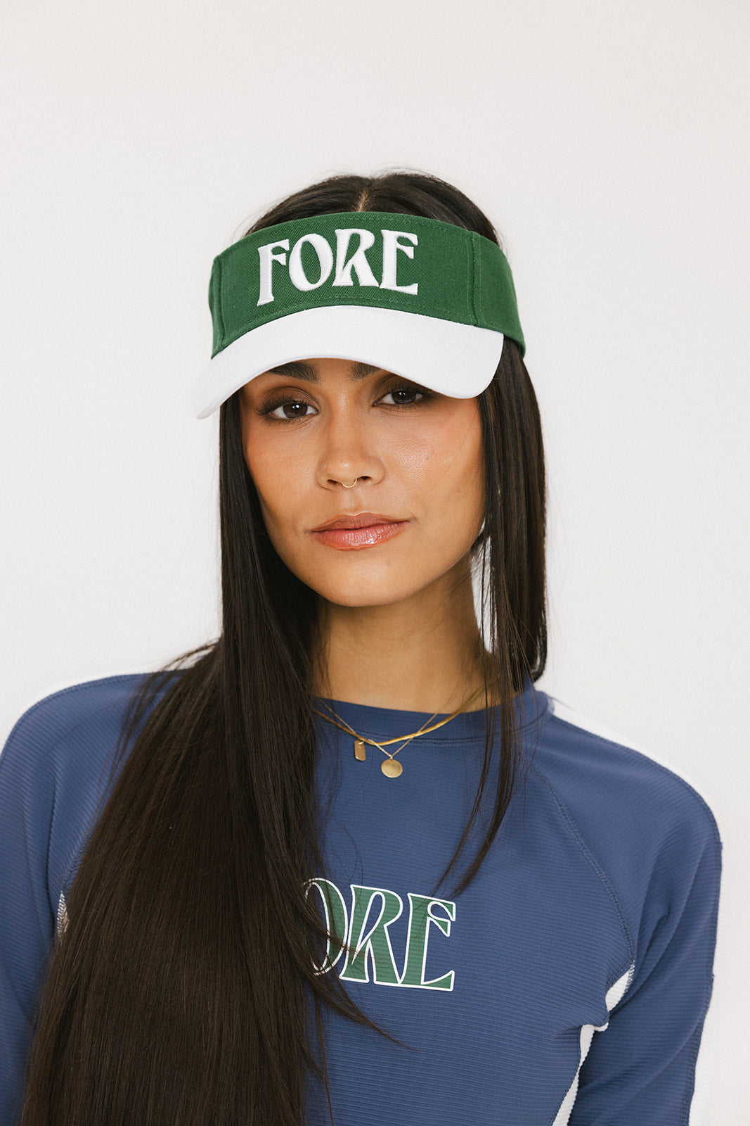 A model wearing a green and white visor with the text 'FORE' across the front.