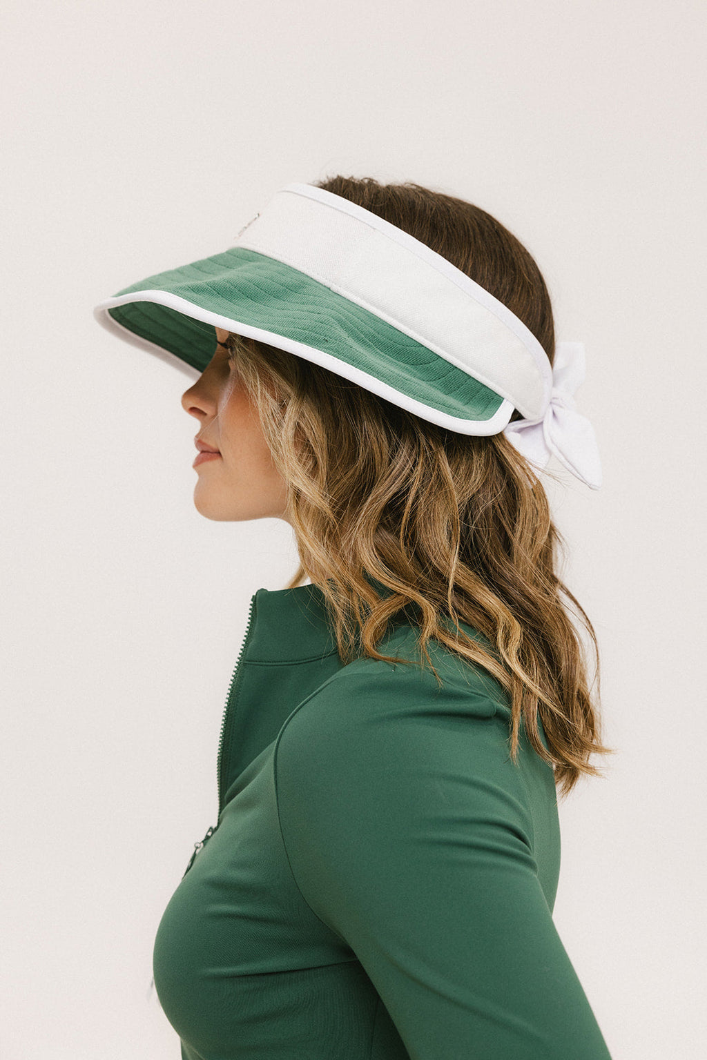 A woman wearing a white and green visor with a 'FA' logo on the front.