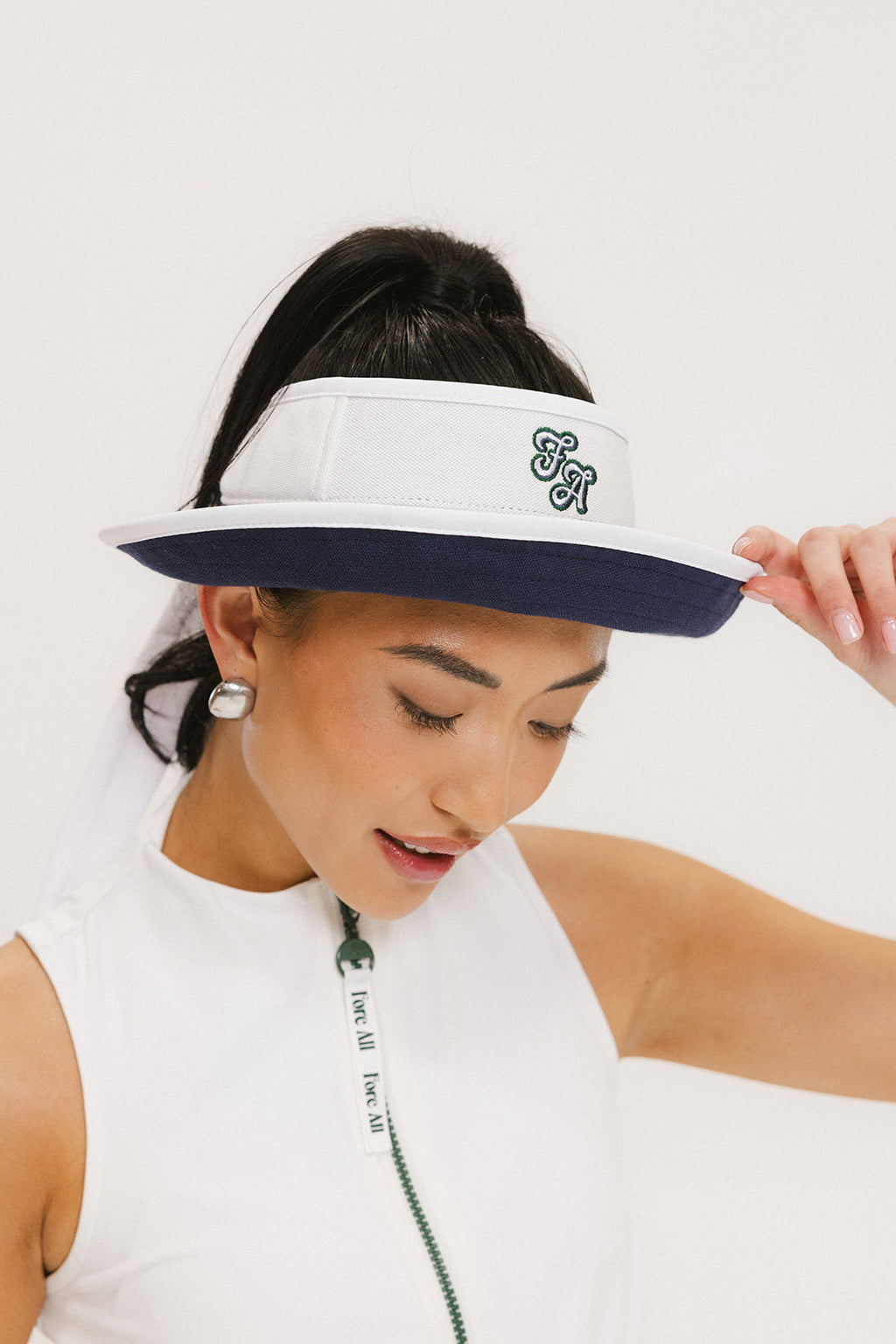 A woman wearing a white and indigo visor with a 'FA' logo on the front and a tied bow on the back.