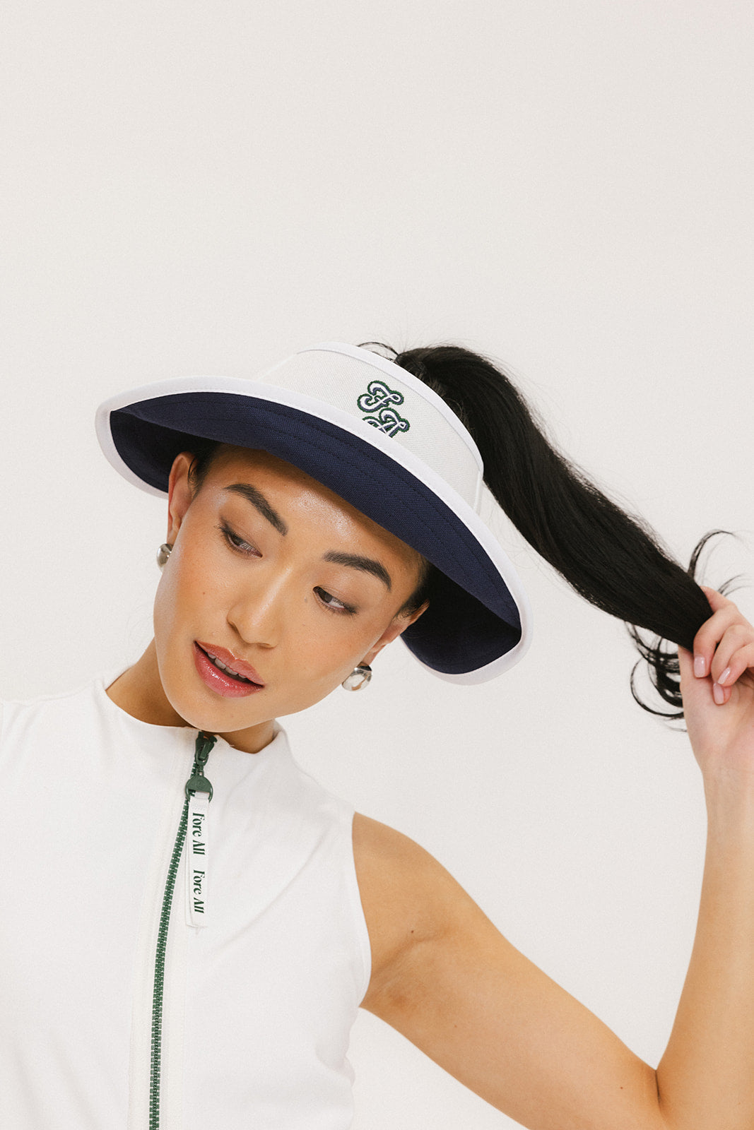 A woman wearing a white and indigo visor with a 'FA' logo on the front and a tied bow on the back.