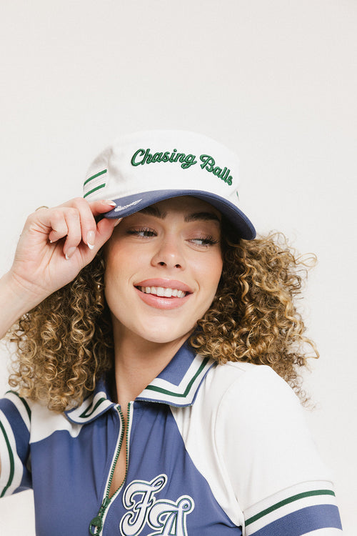A model wearing a white and blue structured cap with 'Chasing Balls' text and stripes.