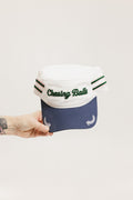 A hand holding a white and blue structured cap with 'Chasing Balls' text and stripes.