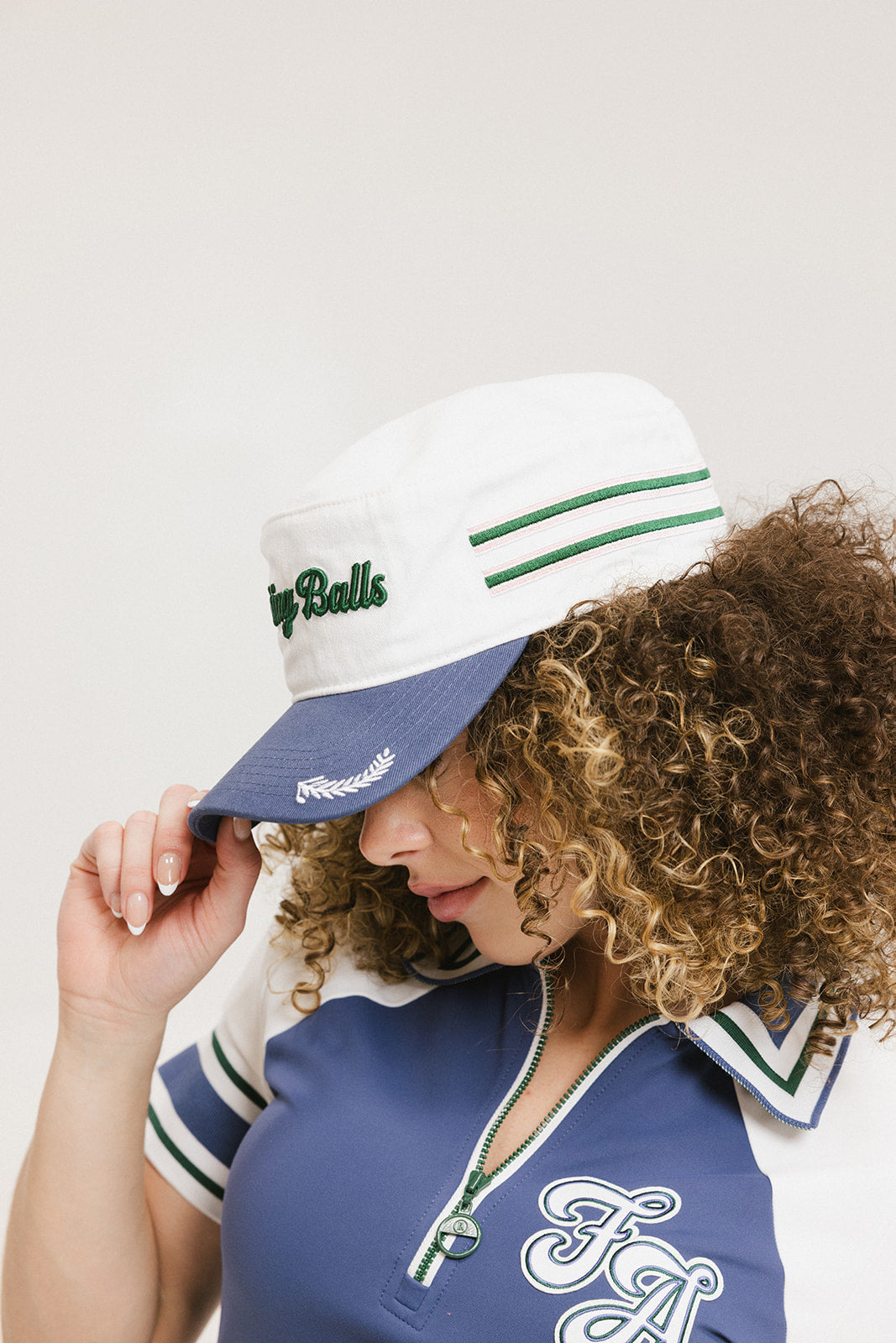 A model wearing a white and blue structured cap with 'Chasing Balls' text and stripes.